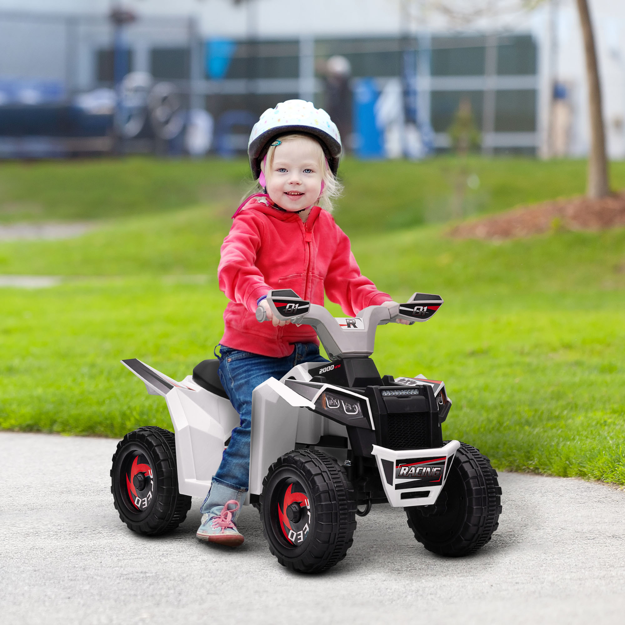 Una niña con sudadera roja y casco monta un quad blanco sobre un camino pavimentado.