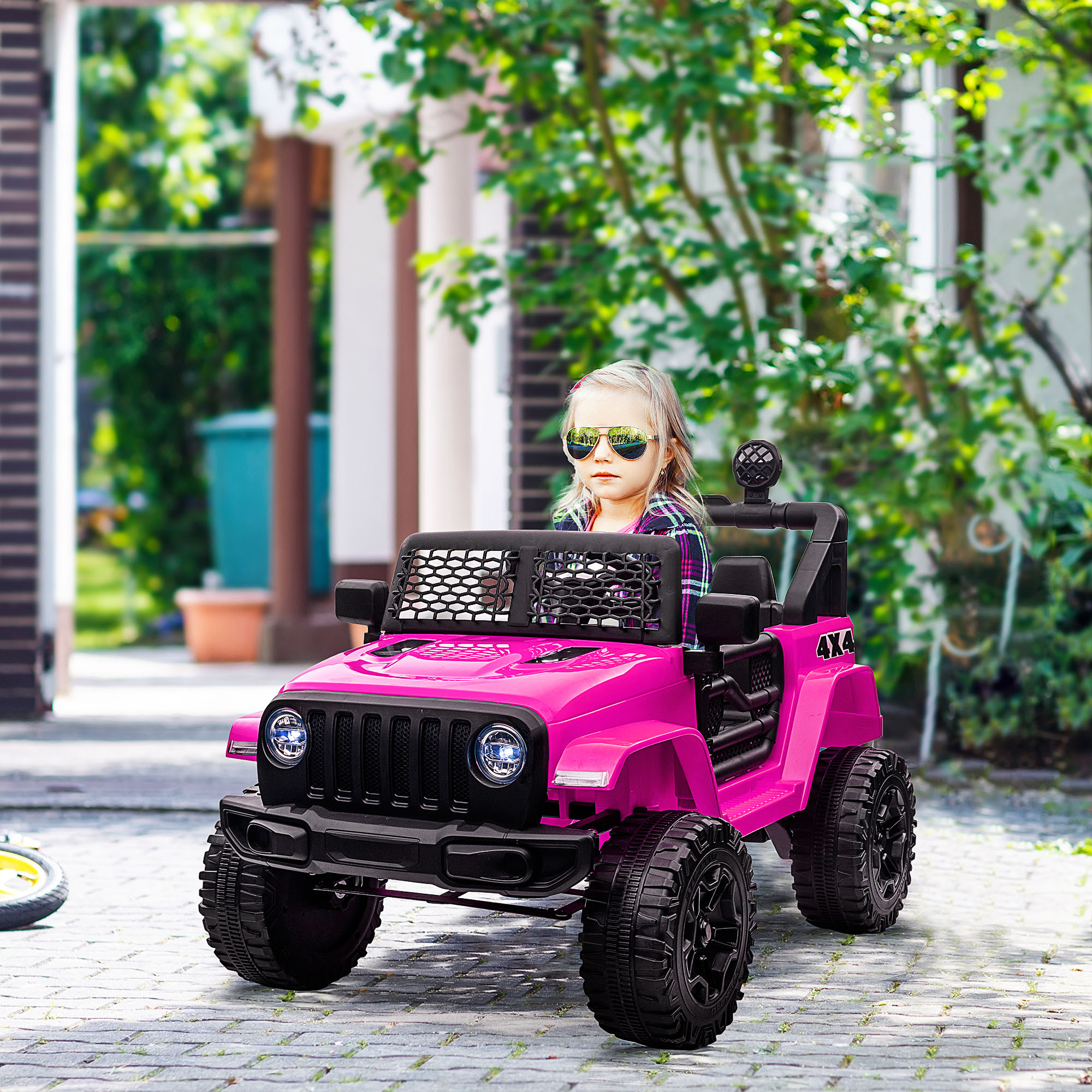 Una niña conduce un jeep de juguete rosa en un camino pavimentado.
