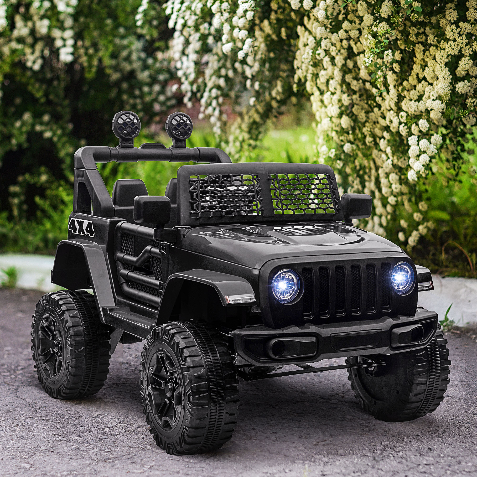 Jeep negro con emblema 4x4 sobre camino de grava frente a arbusto en flor.