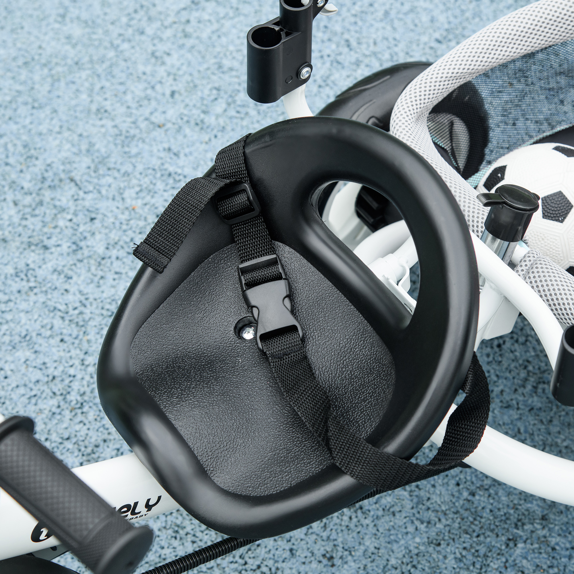Asiento negro para niños con correas en un triciclo blanco.