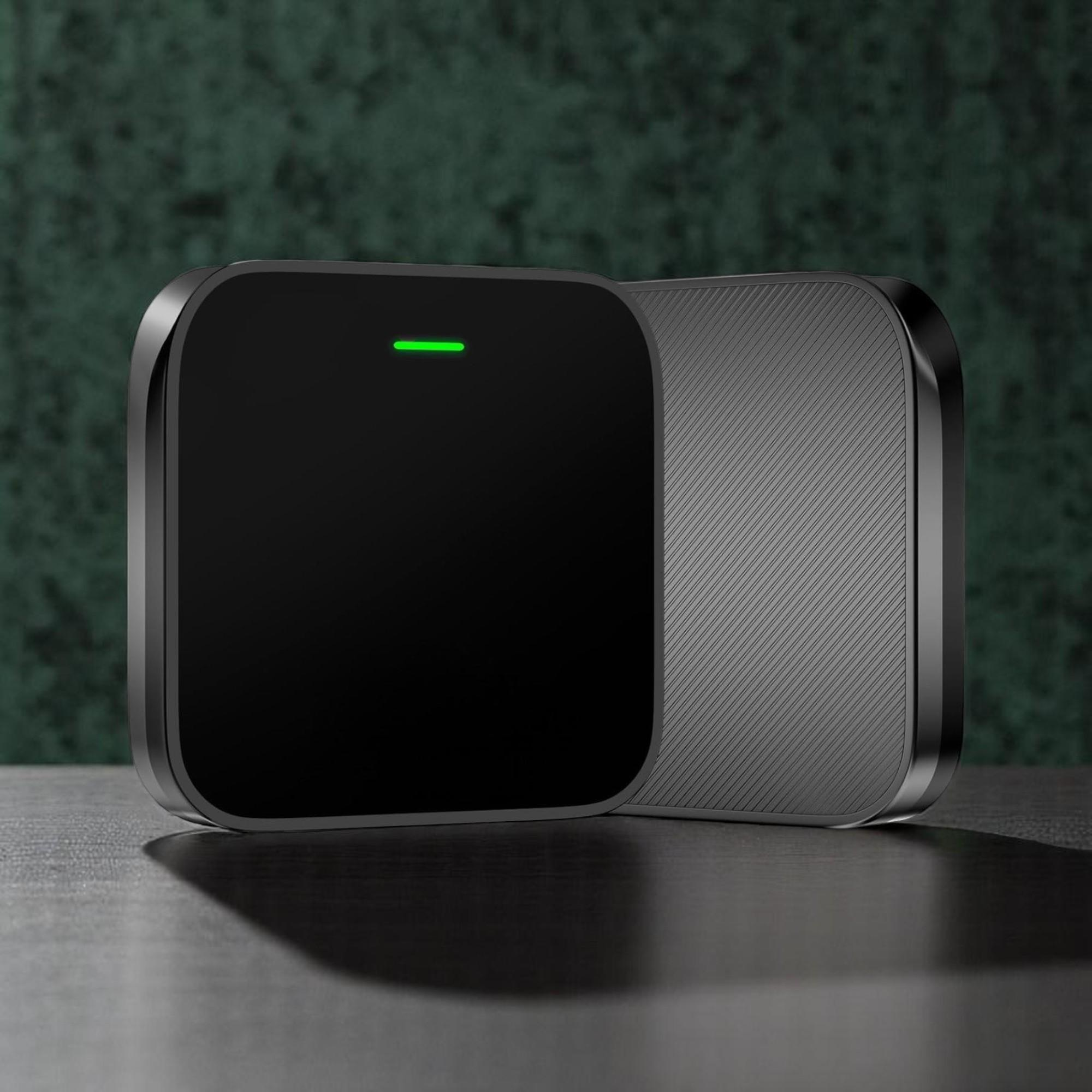 Un dispositivo rectangular negro con una barra LED verde sobre una mesa de madera.
