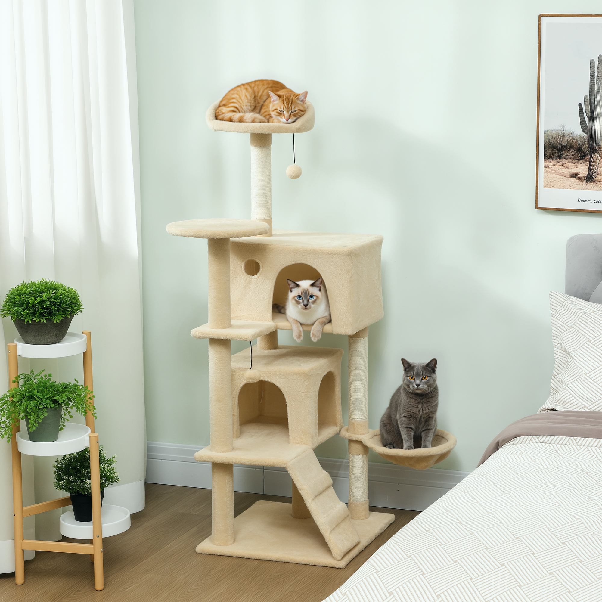 Un árbol rascador beige con tres gatos: uno naranja durmiendo arriba, uno siamés en una caseta y uno gris abajo.