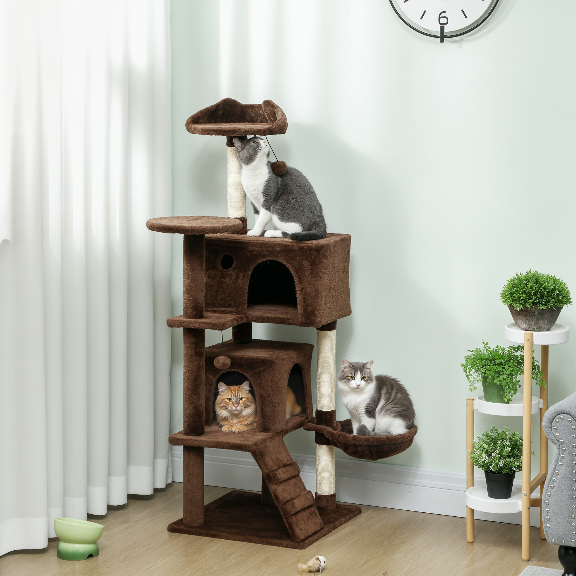 Árbol rascador marrón con tres gatos: uno arriba, uno en una casa, uno en una hamaca.