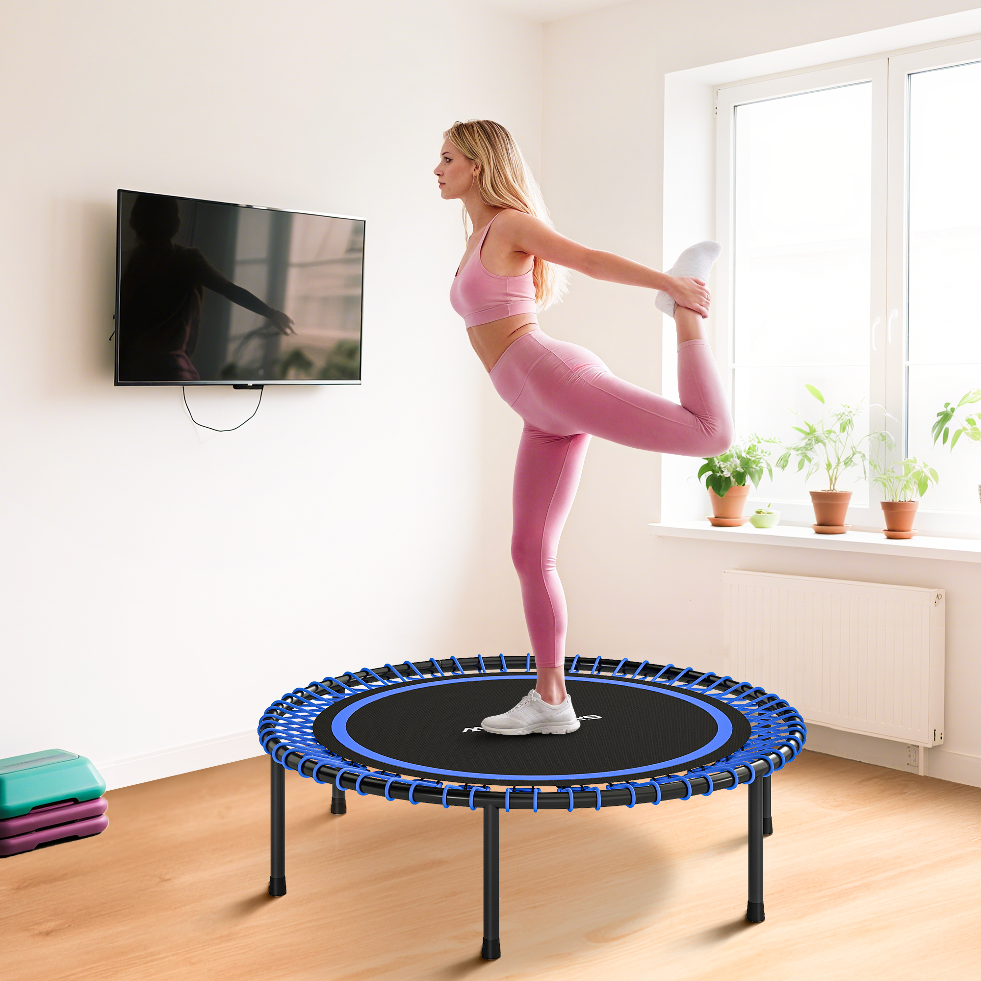 Mujer en ropa deportiva rosa estirándose en un mini trampolín azul.