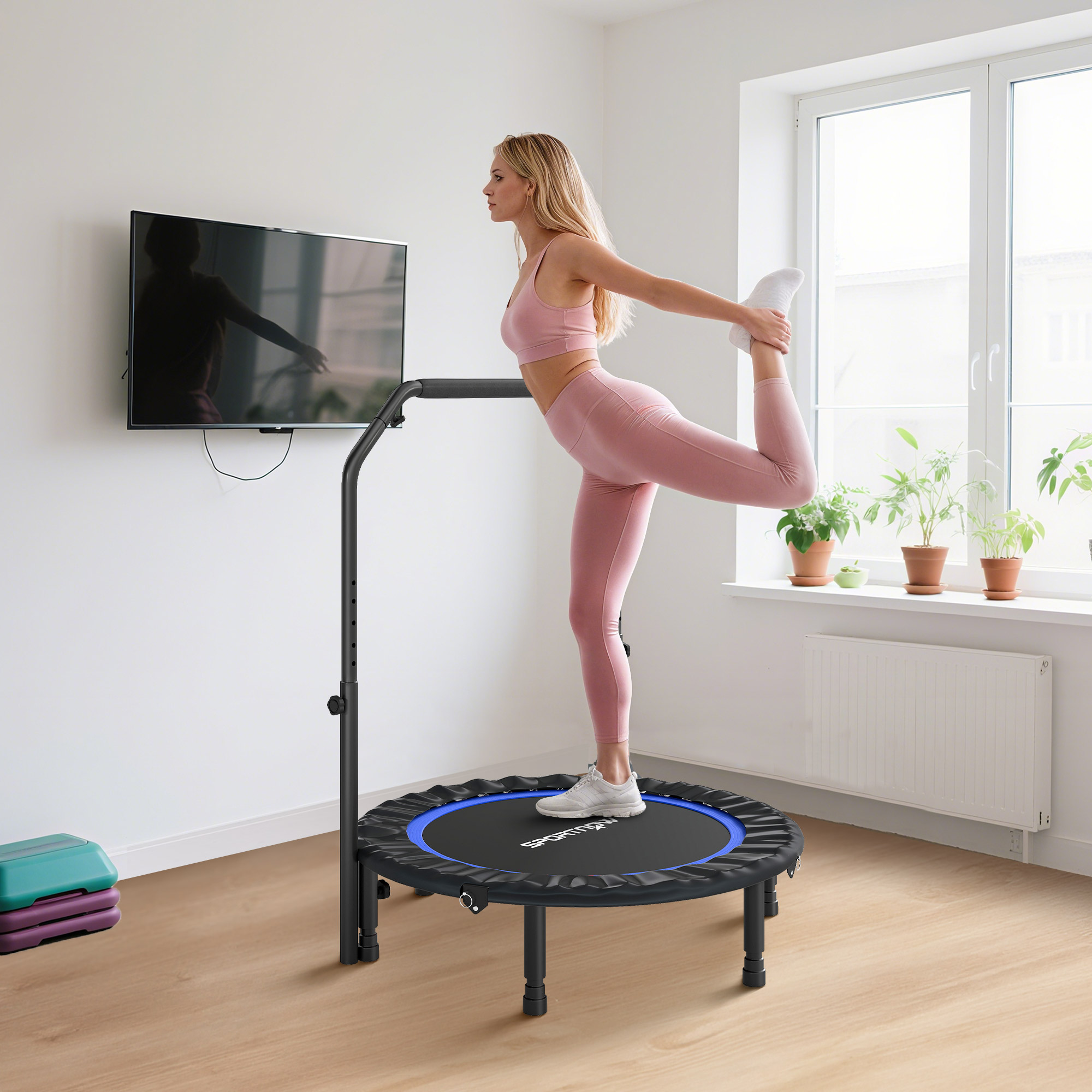 Mujer estirándose en un trampolín con barra en una habitación luminosa.