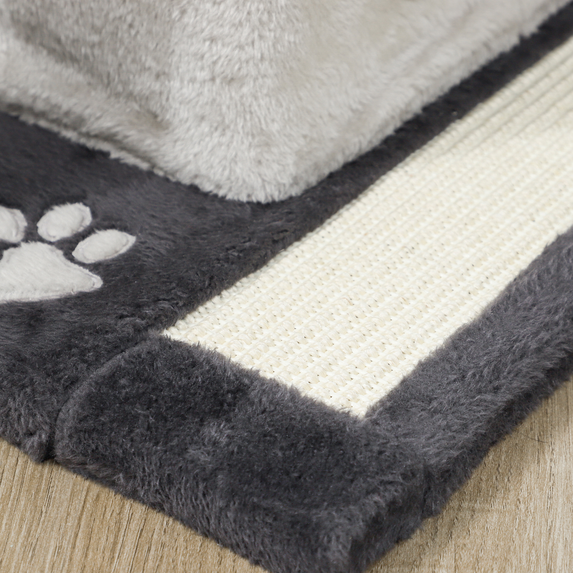 Juguete gris para gatos con huella y rascador sobre madera.