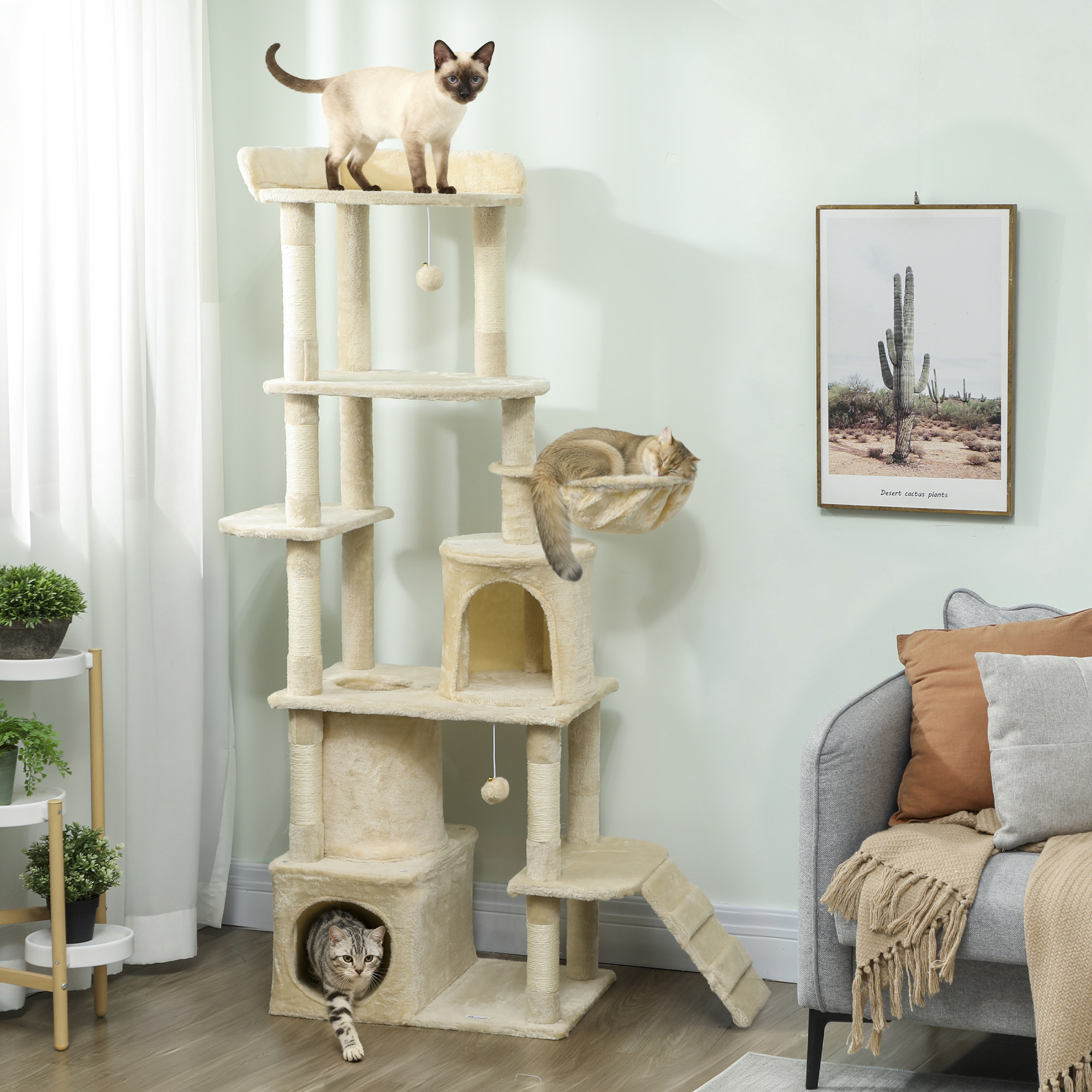 Un árbol rascador beige alto con tres gatos; al lado hay un sofá con cojines.