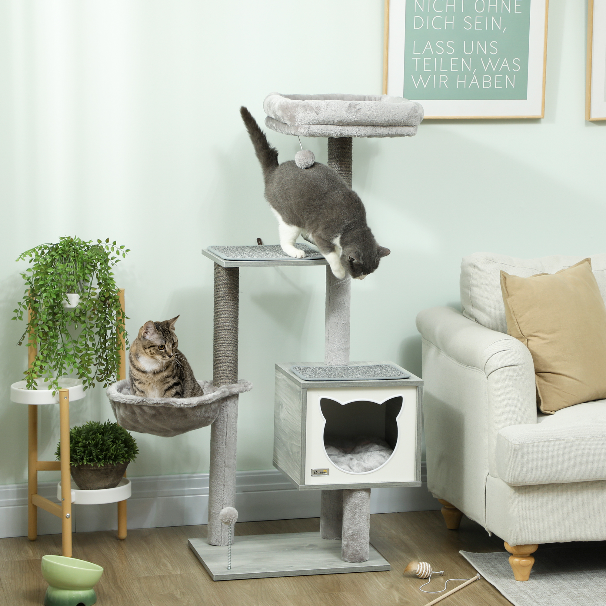Dos gatos en un árbol para gatos con hamaca y casa.