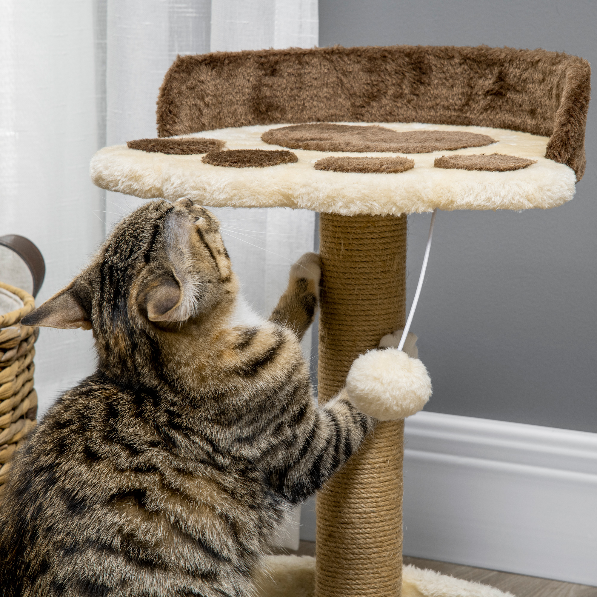 Un gato atigrado juega con un rascador con bolas peludas.