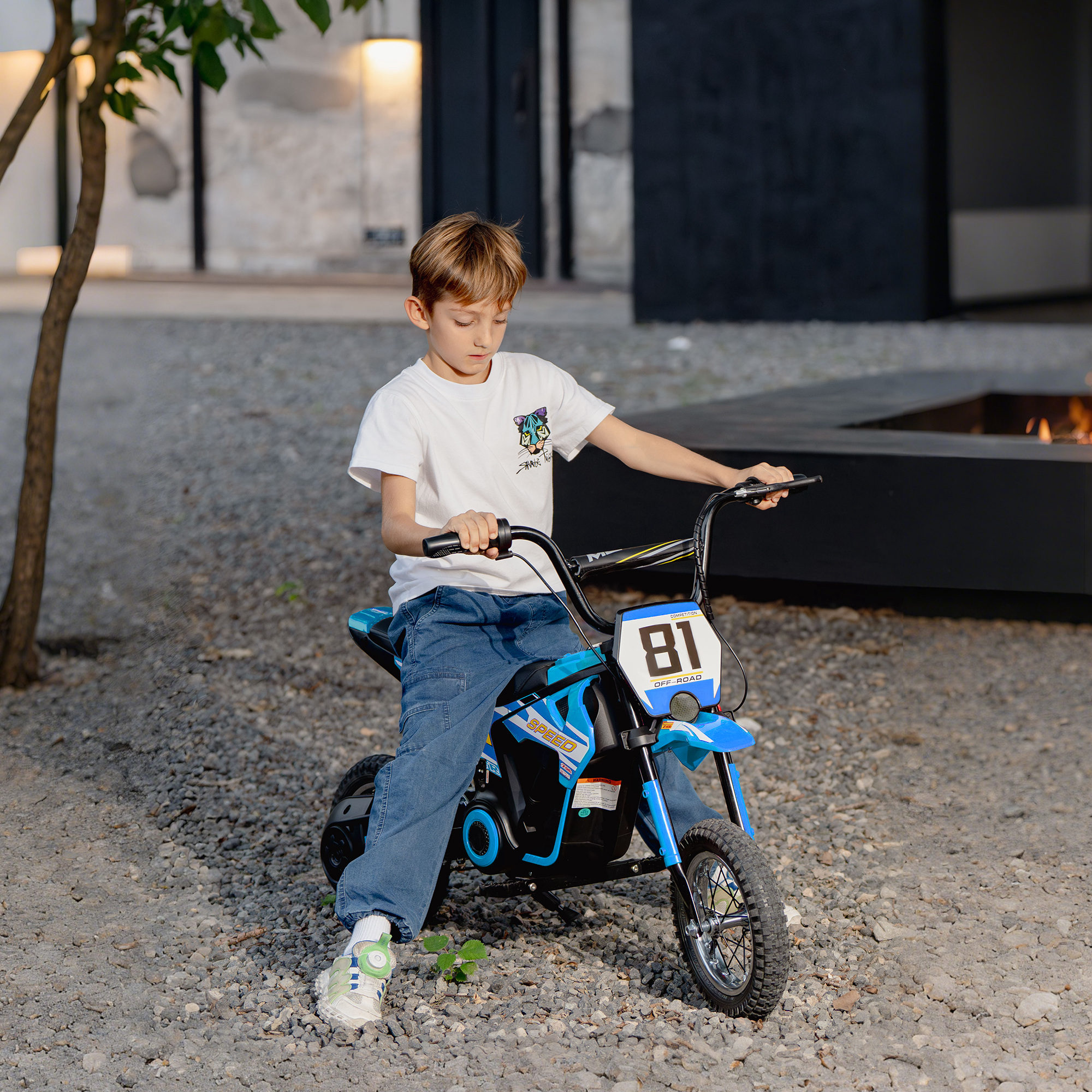 Un niño se sienta en una motocicleta de juguete azul al aire libre.