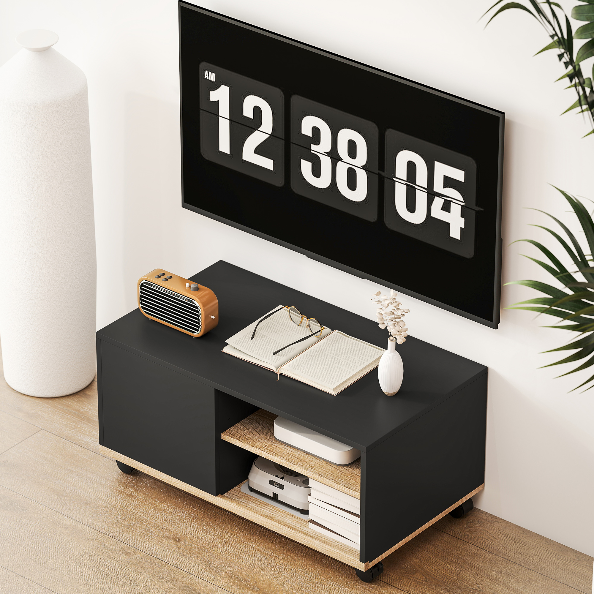 Un moderno mueble de TV negro con pantalla de reloj flip, radio, libro y jarrón.