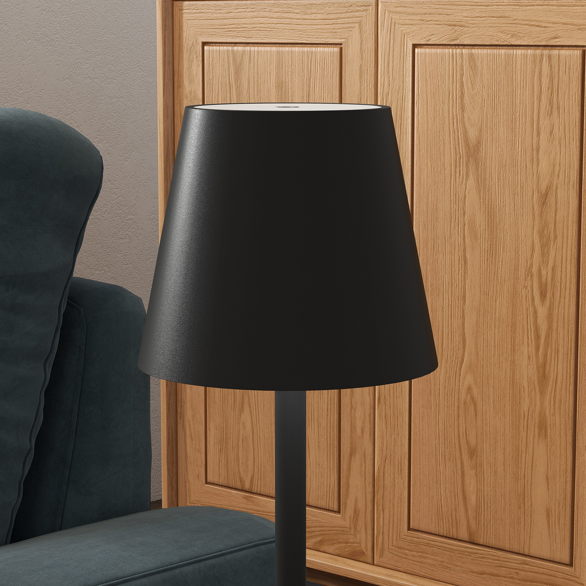 Una lámpara negra está junto a un sillón azul oscuro frente a un armario de madera.