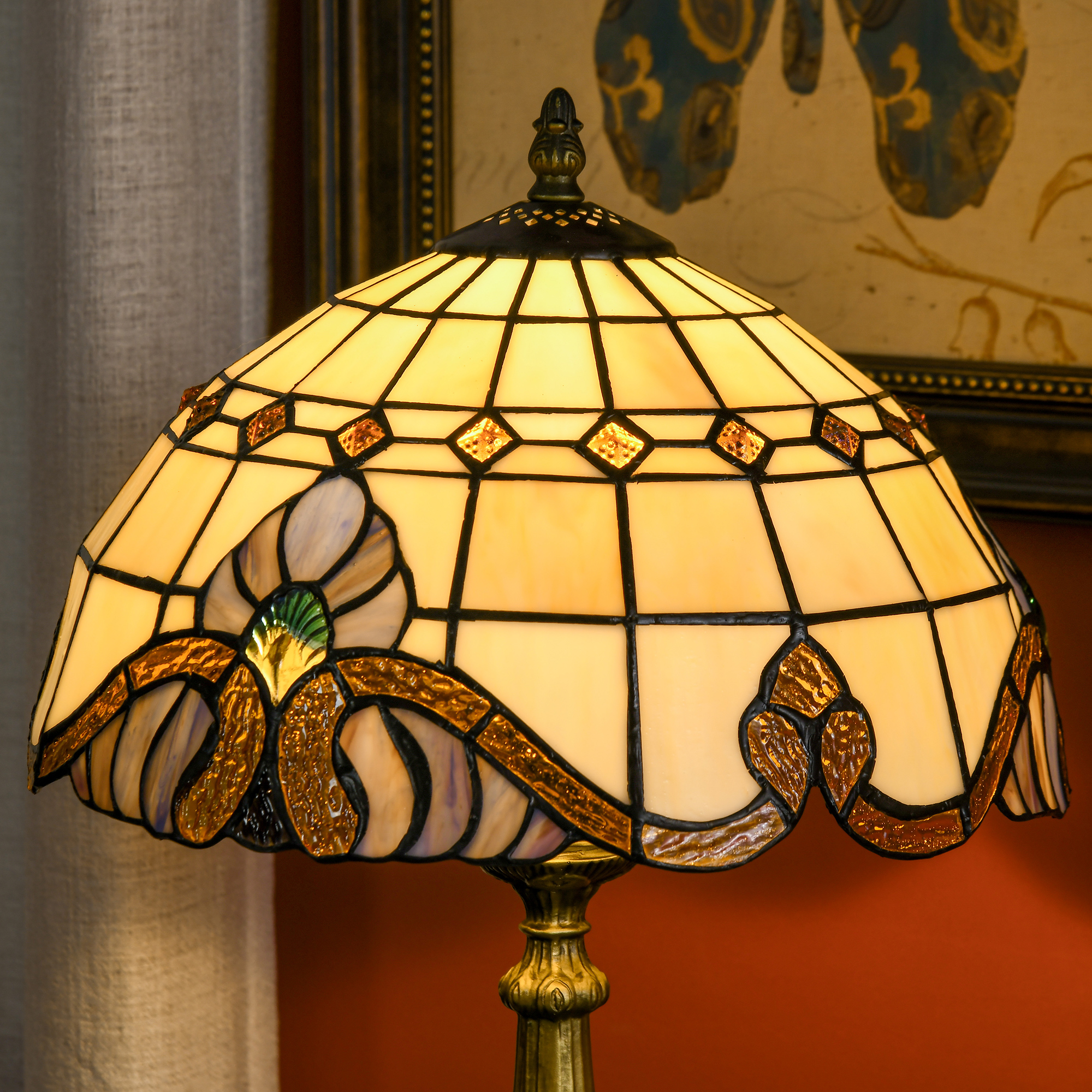 Una lámpara Tiffany con pantalla color crema decorada con piezas de vidrio marrones y azules.