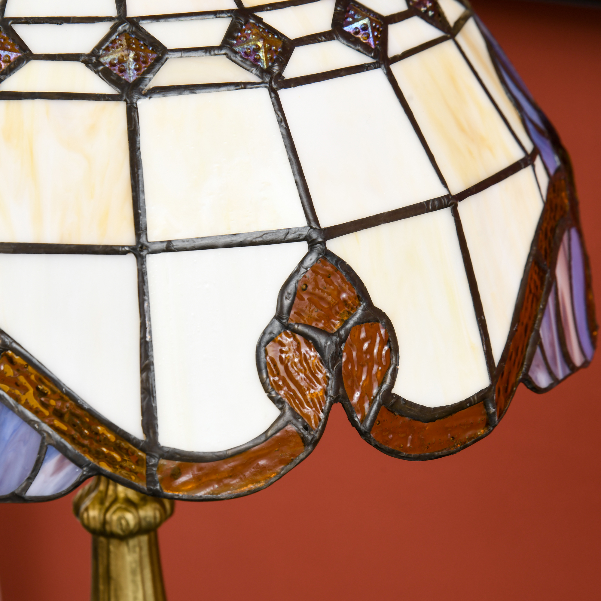 Una lámpara Tiffany con paneles de vidrio blancos y ámbar, decorada con detalles marrones.