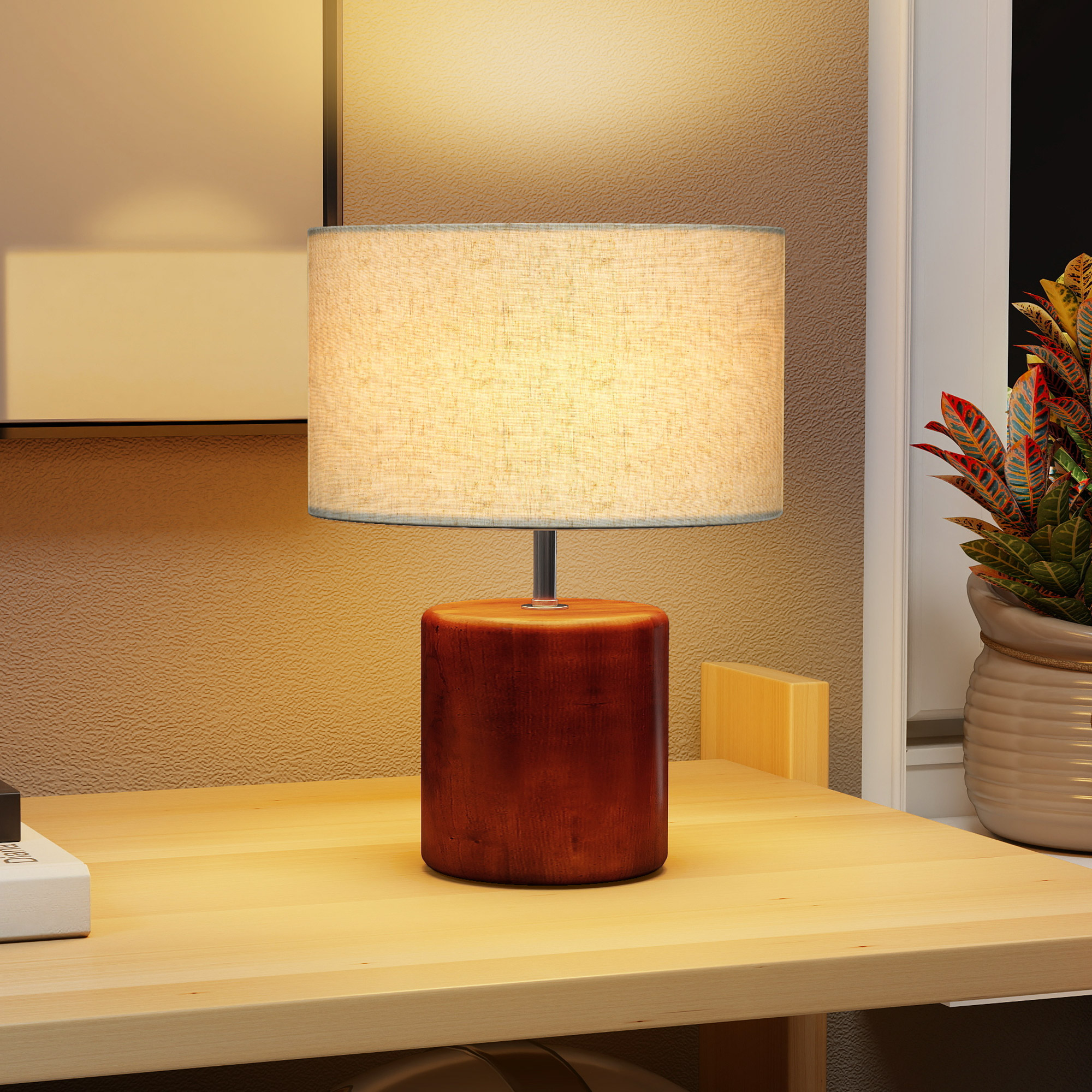 Una lámpara de noche con base de madera brilla sobre un escritorio junto a una planta.