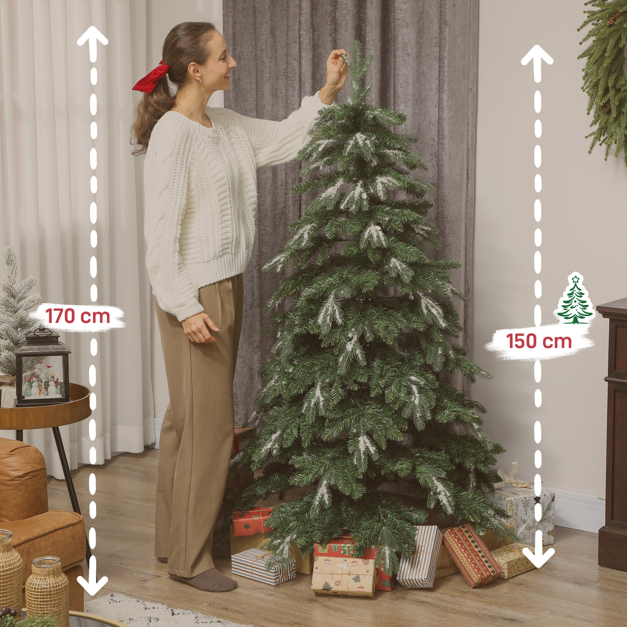 Mujer decorando árbol de Navidad con acentos de nieve, regalos debajo.