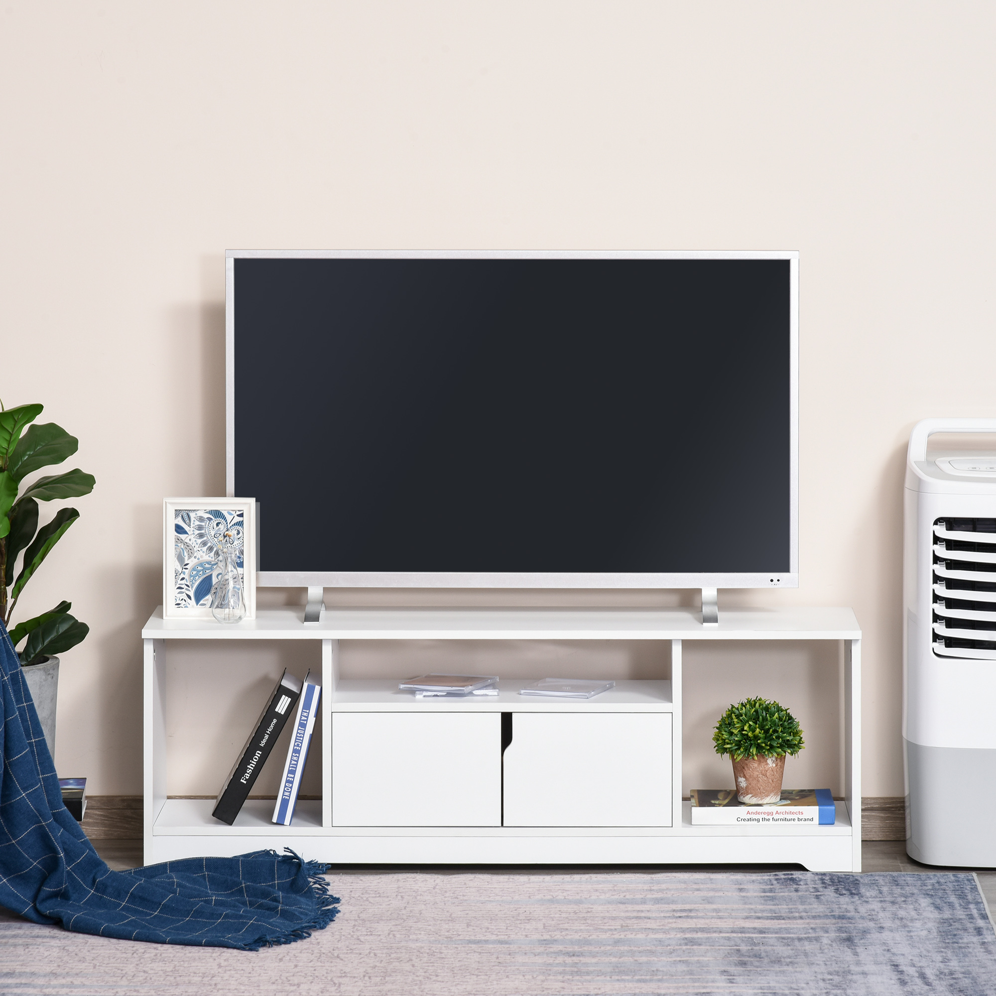 Un mueble de TV blanco moderno con TV, plantas y libros.