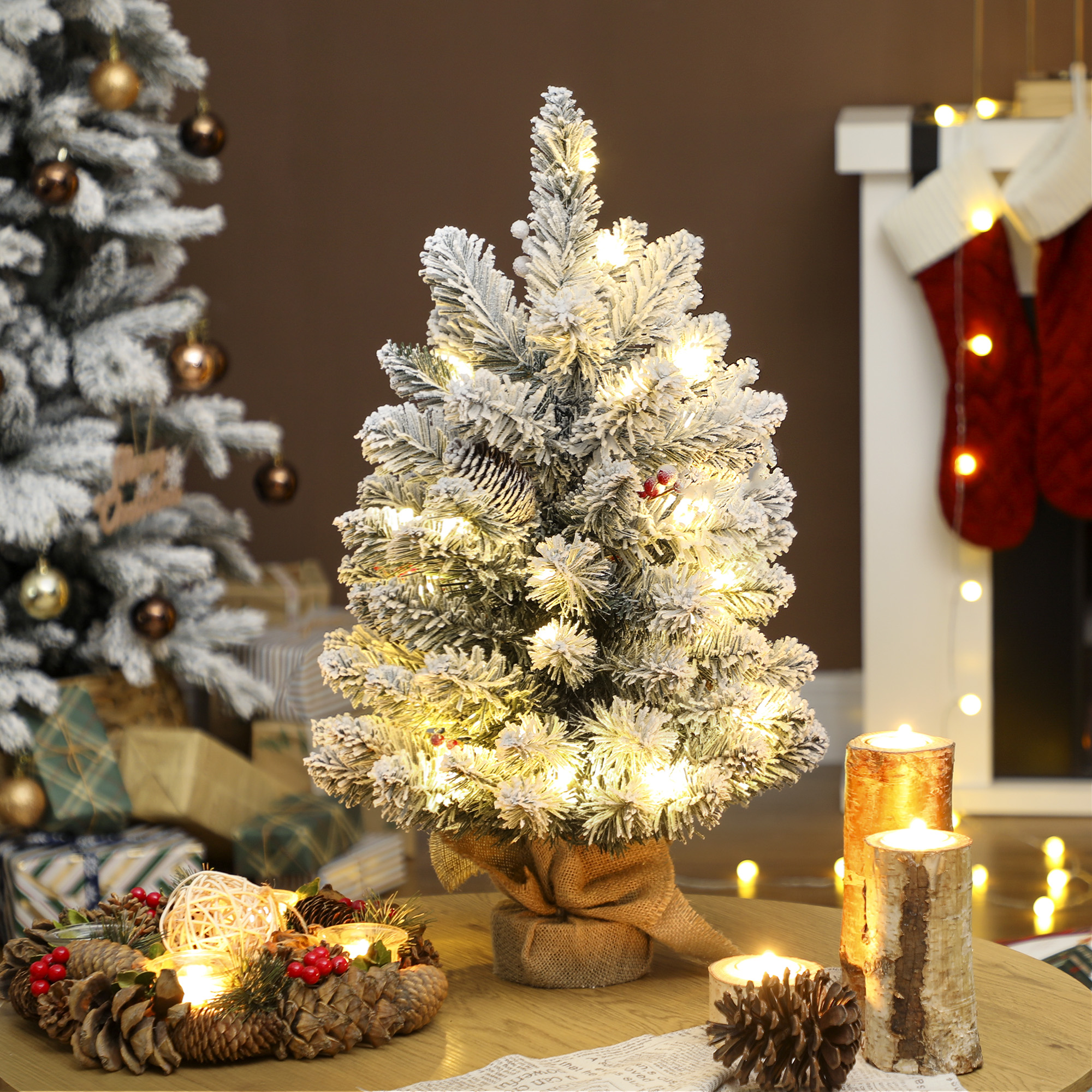 Un pequeño árbol de Navidad iluminado con efecto nevado está sobre una mesa.