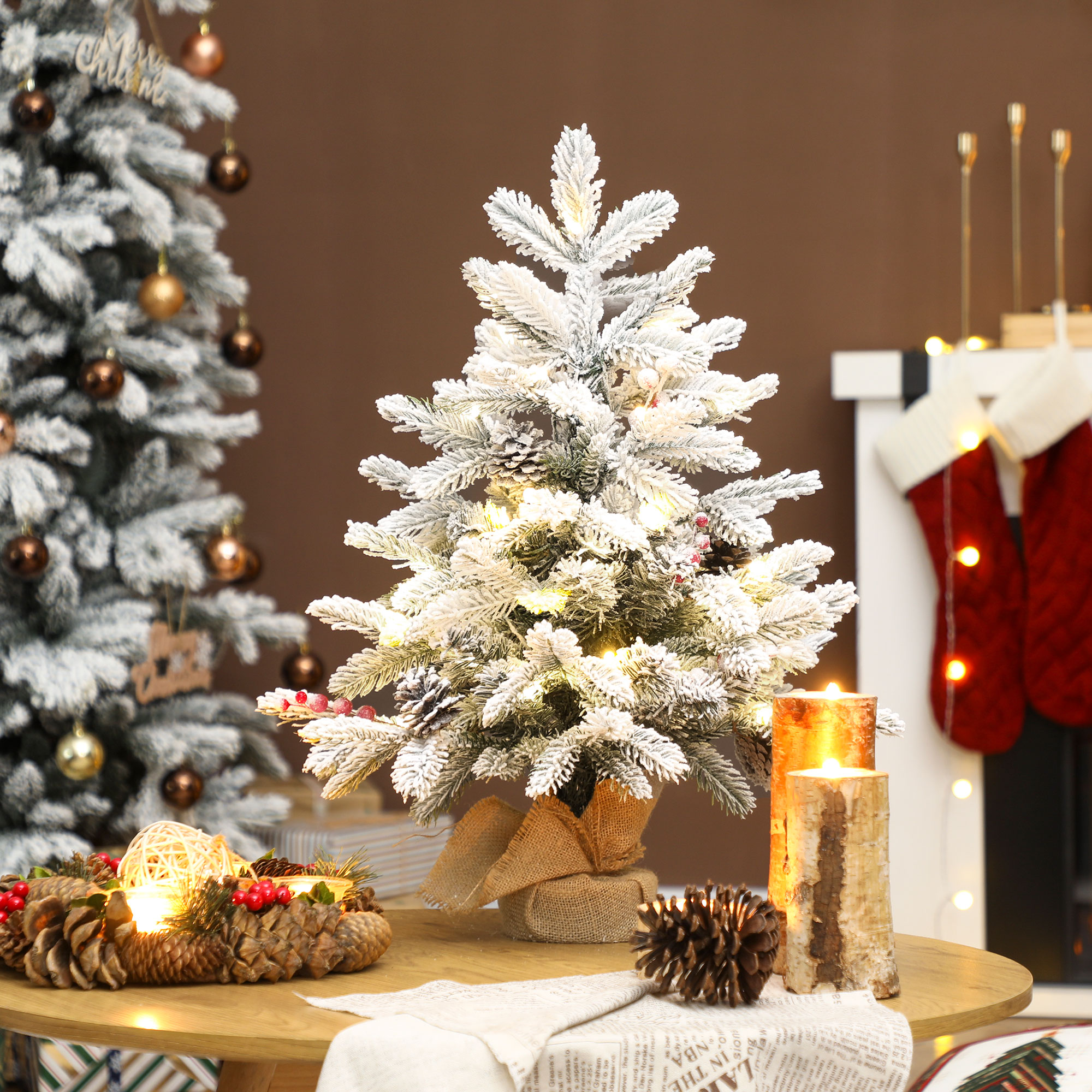 Un pequeño árbol de Navidad cubierto de nieve con luces está sobre una mesa de madera.