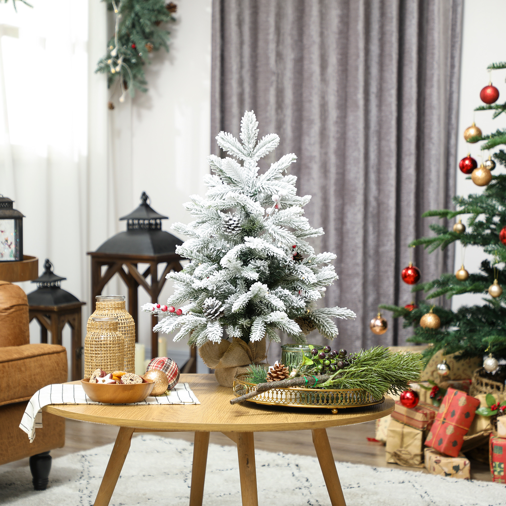 Un árbol de Navidad pequeño y nevado se sienta en una mesa de madera con galletas y decoración.