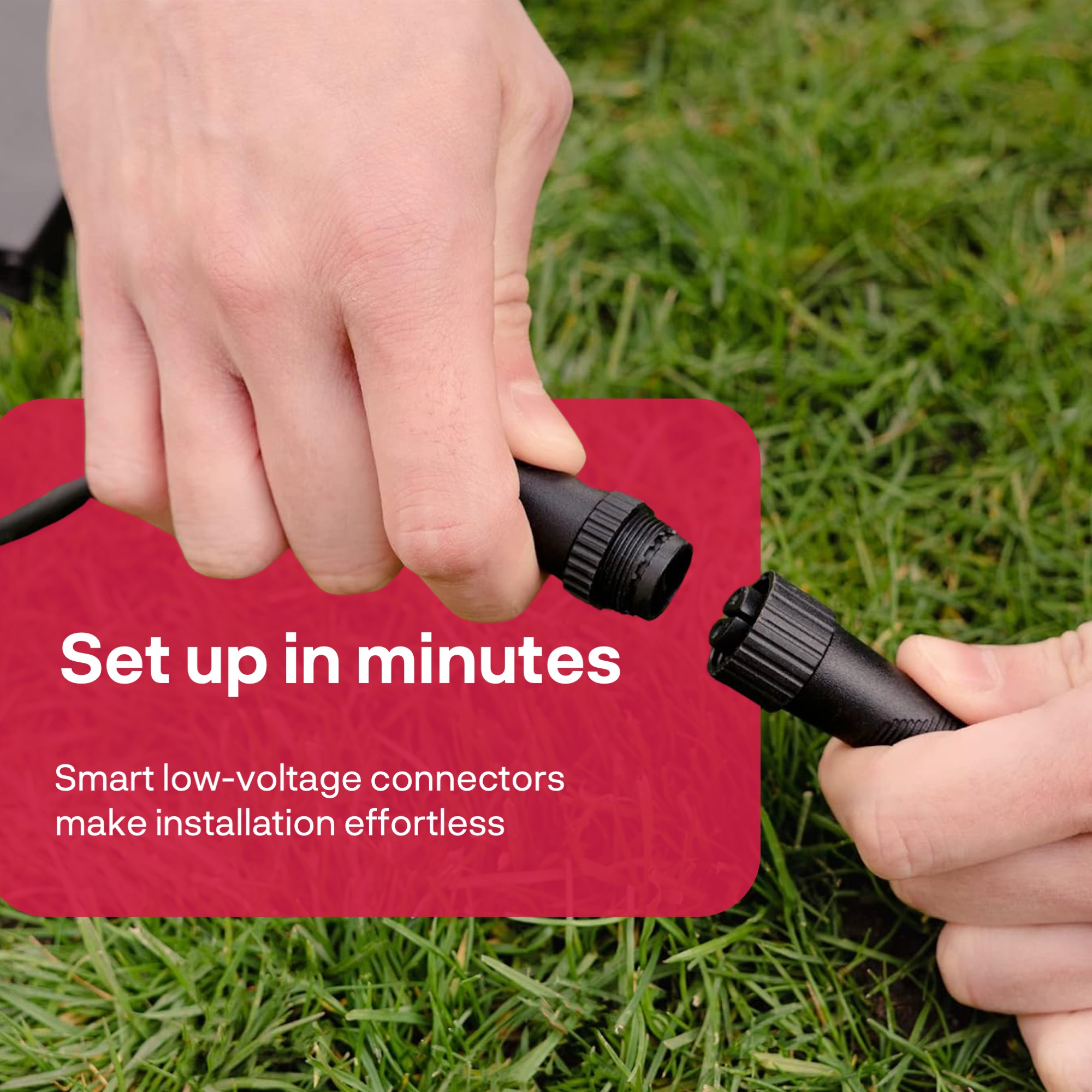 Hands connect two black plugs on grass.