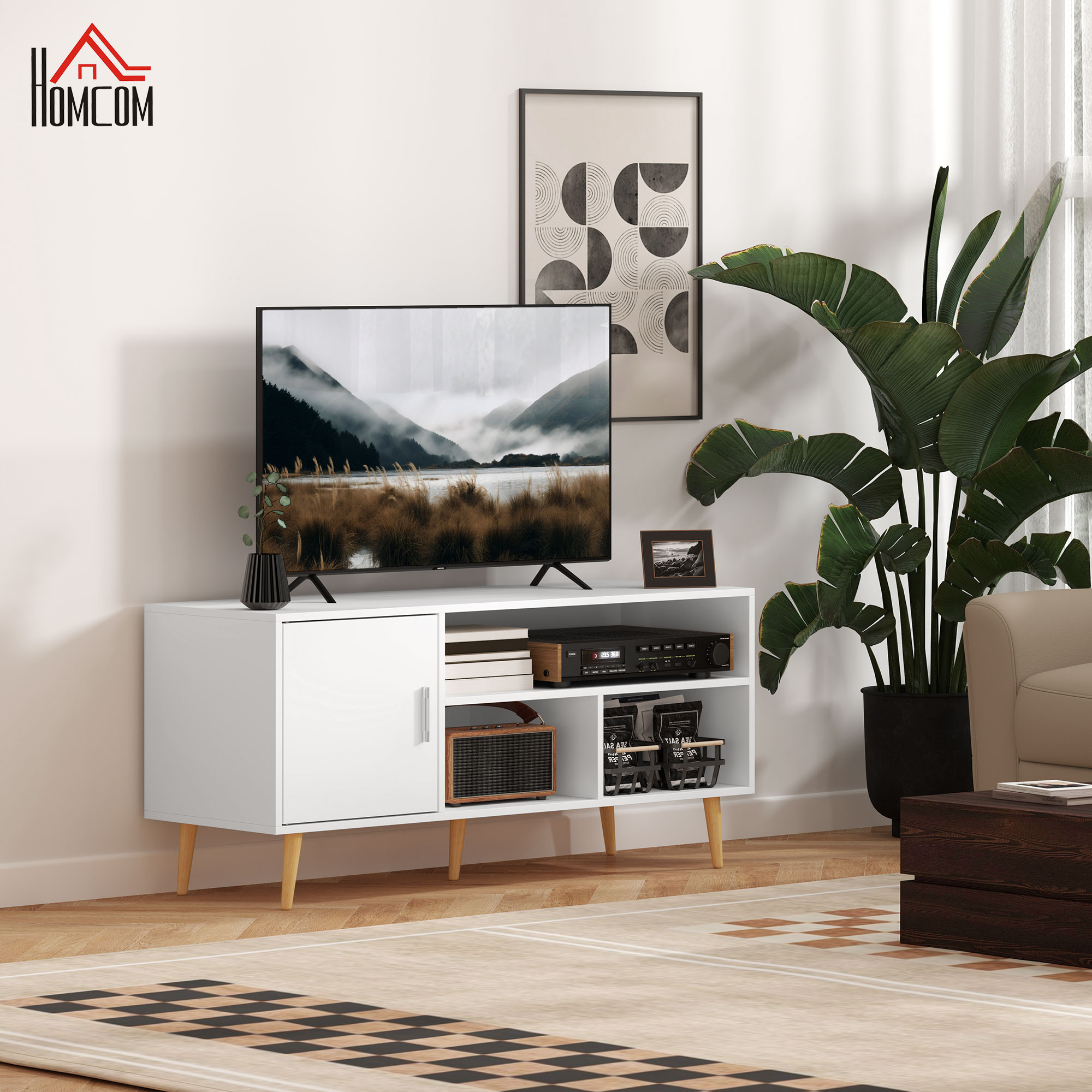 Un mueble de TV blanco con un televisor, altavoz y objetos decorativos.