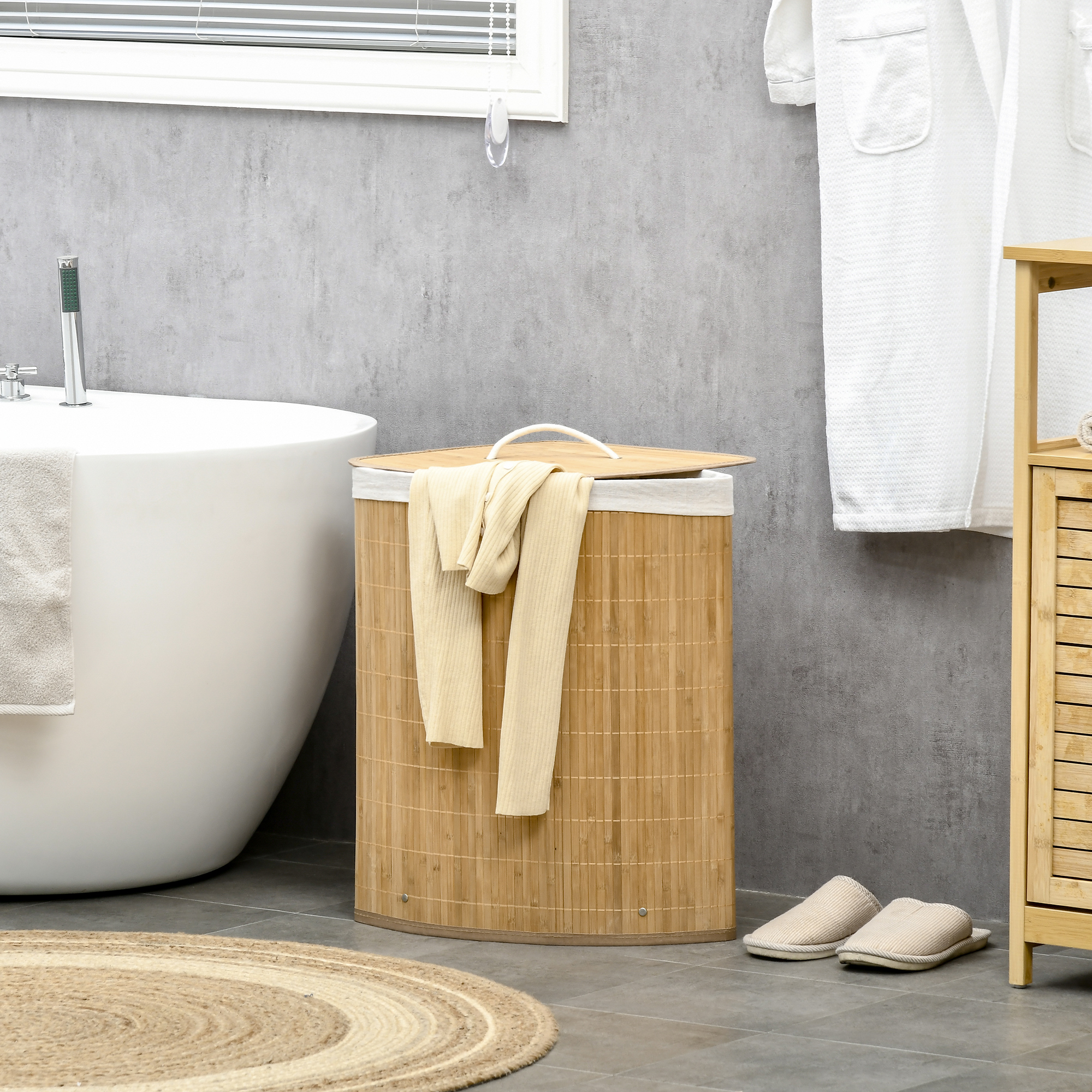 Un baño blanco con cesto de ropa de bambú, bañera, toallas y zapatillas.