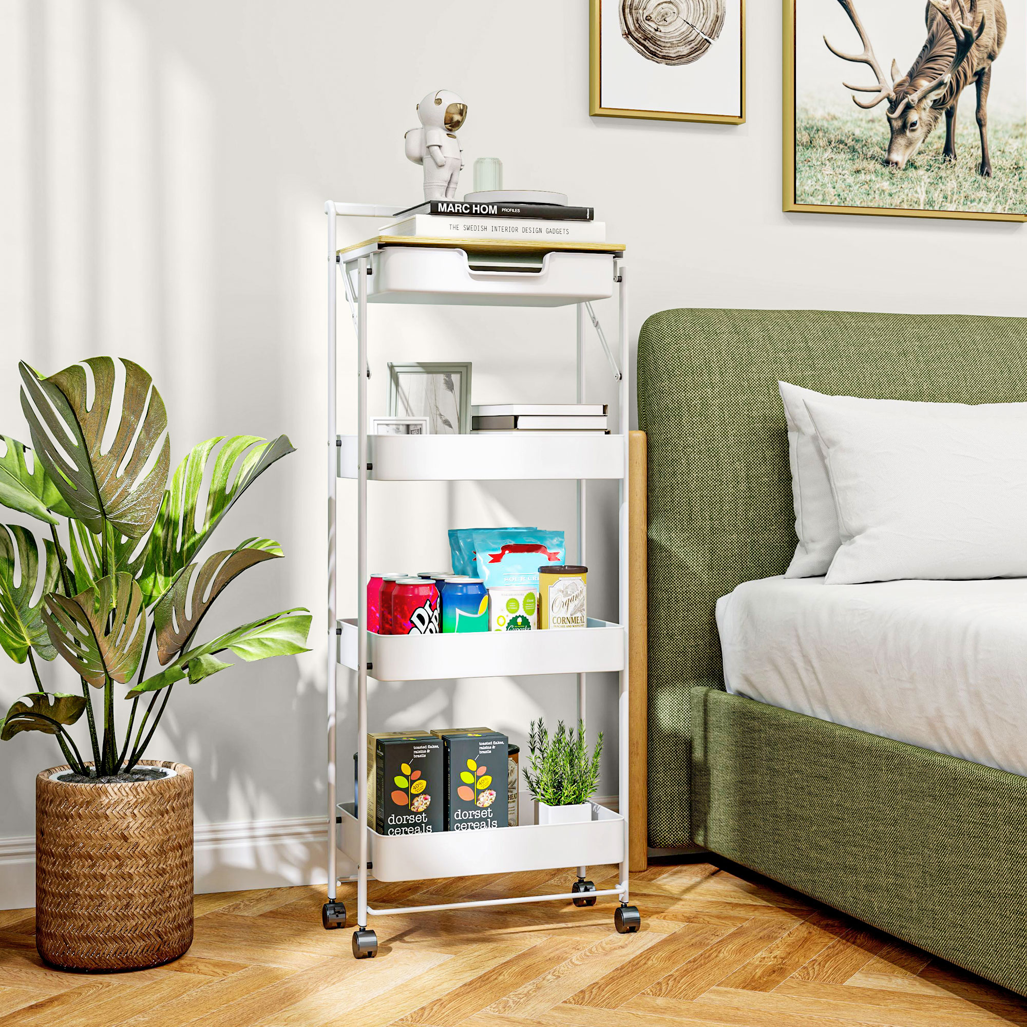 Un carrito blanco con ruedas junto a una cama con cabecero verde, lleno de comestibles y libros.