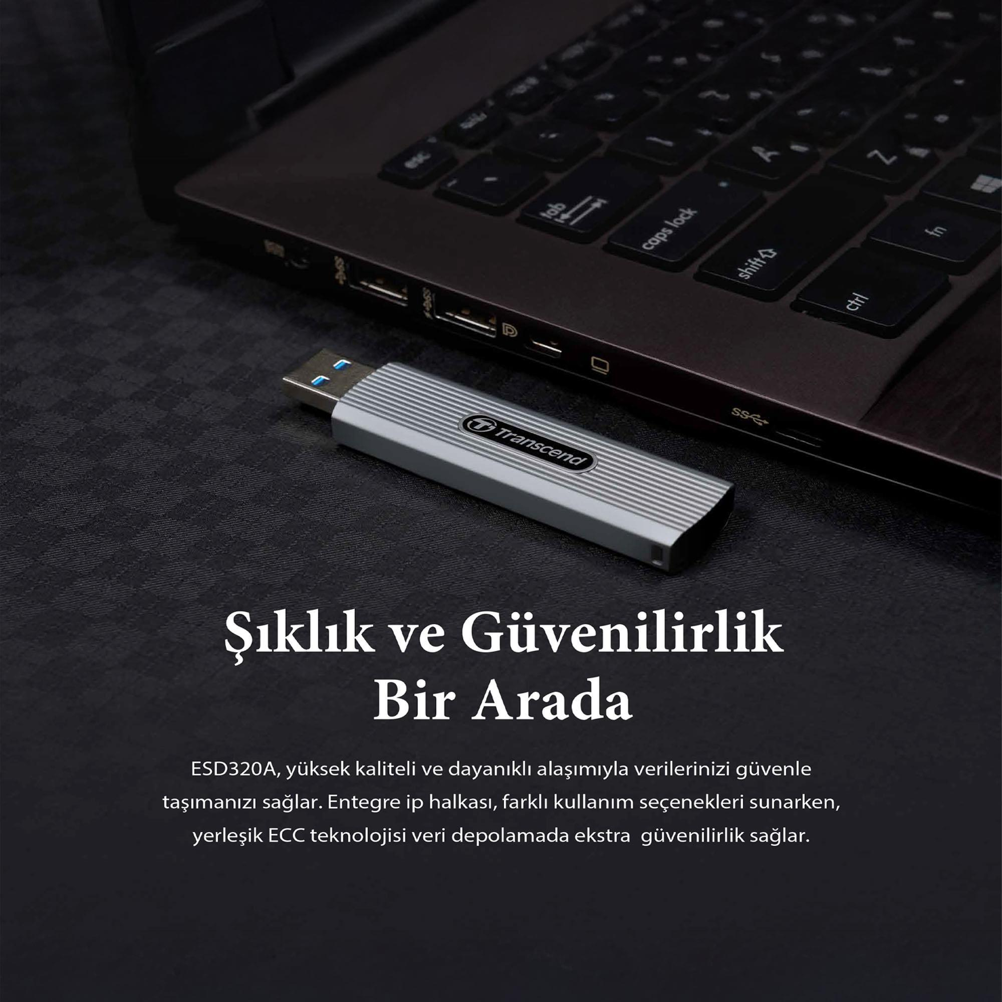 A silver USB drive rests beside a laptop keyboard on a black textured surface.