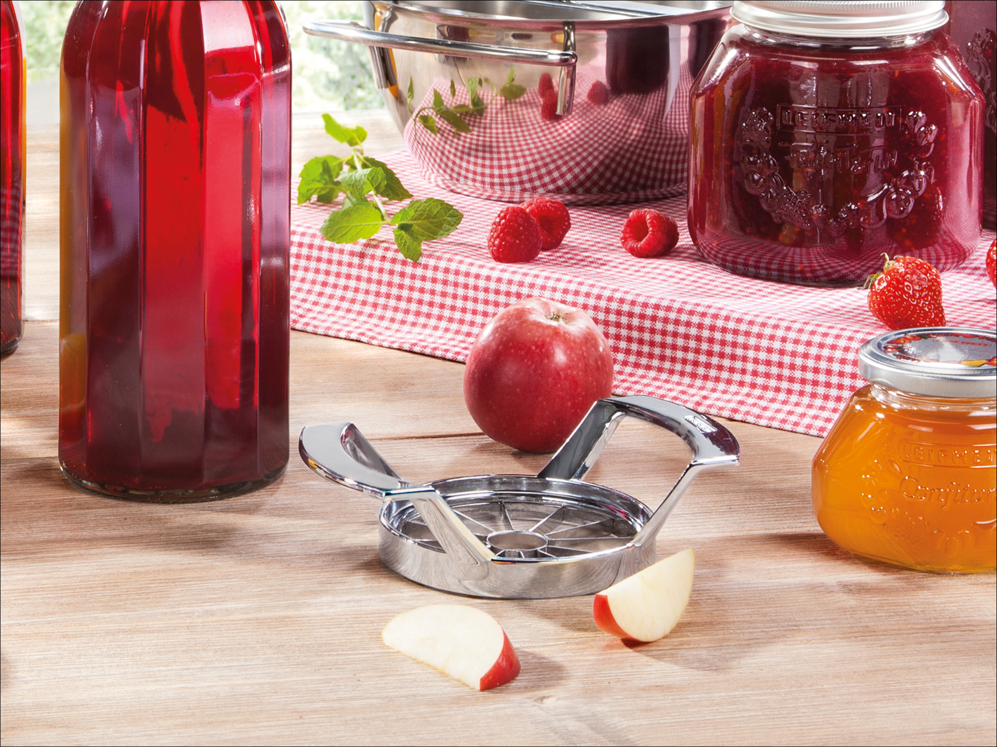 Bottiglia rossa, tagliacore, spicchi di mela, mela, lamponi, fragola, barattolo di miele, barattolo di marmellata.