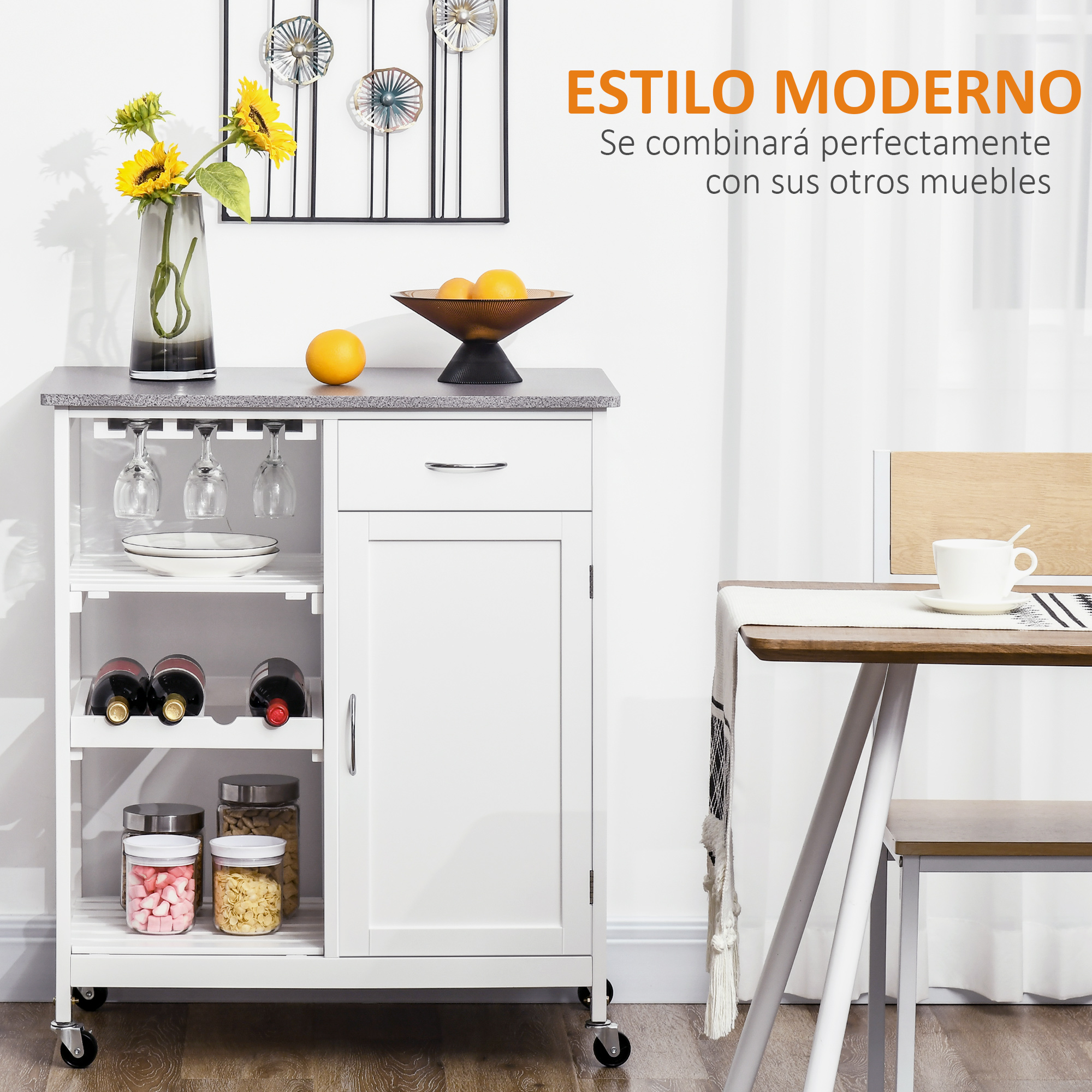 Un carrito de cocina blanco con vasos, botellas, tarros y flores. Una mesa está al lado.