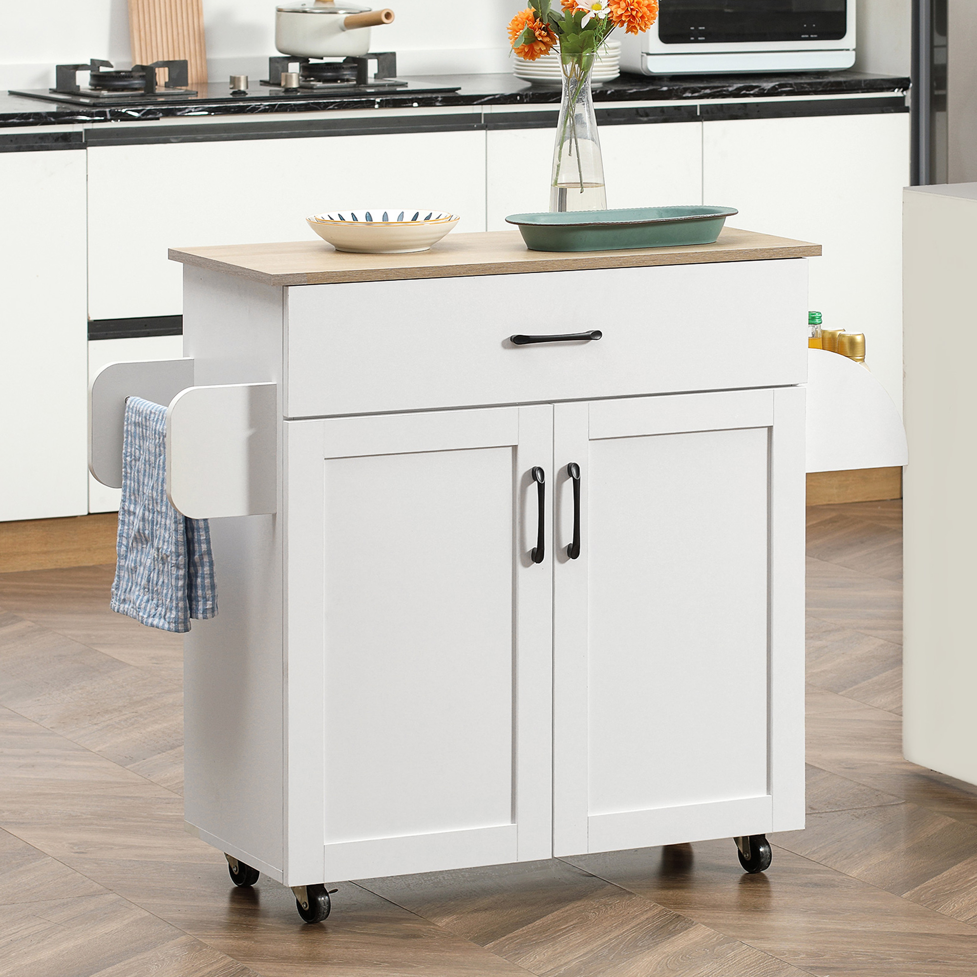 Un carrito de cocina blanco con tapa de madera, cajón, dos puertas y toallero.