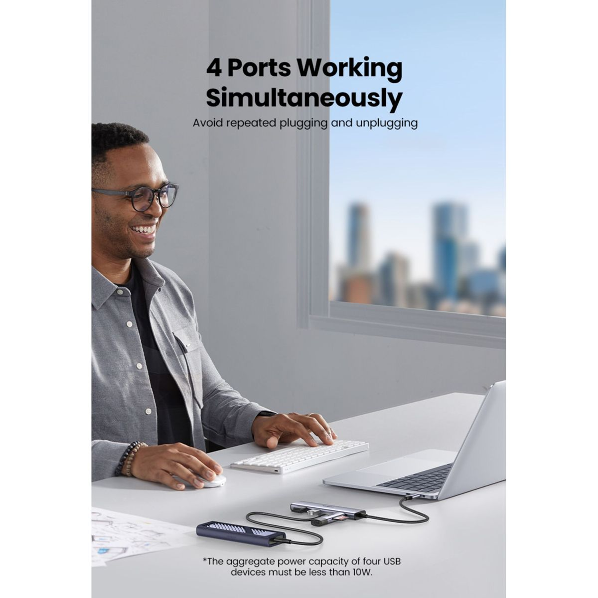 Mężczyzna pracuje przy biurku z laptopem i hubami USB, 4 porty jednocześnie.