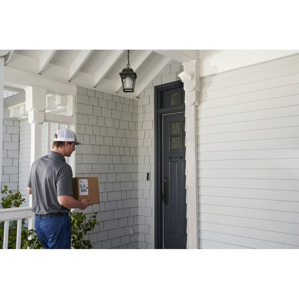 Listonosz z paczką stoi przed drzwiami wejściowymi.