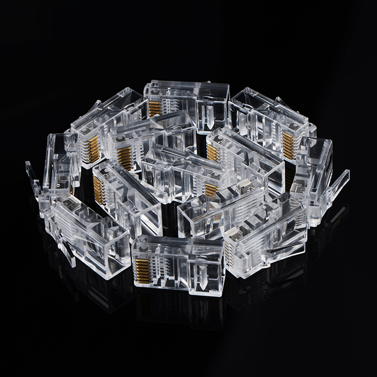 Stos przezroczystych złączy RJ45 ze złotymi stykami na czarnym tle.