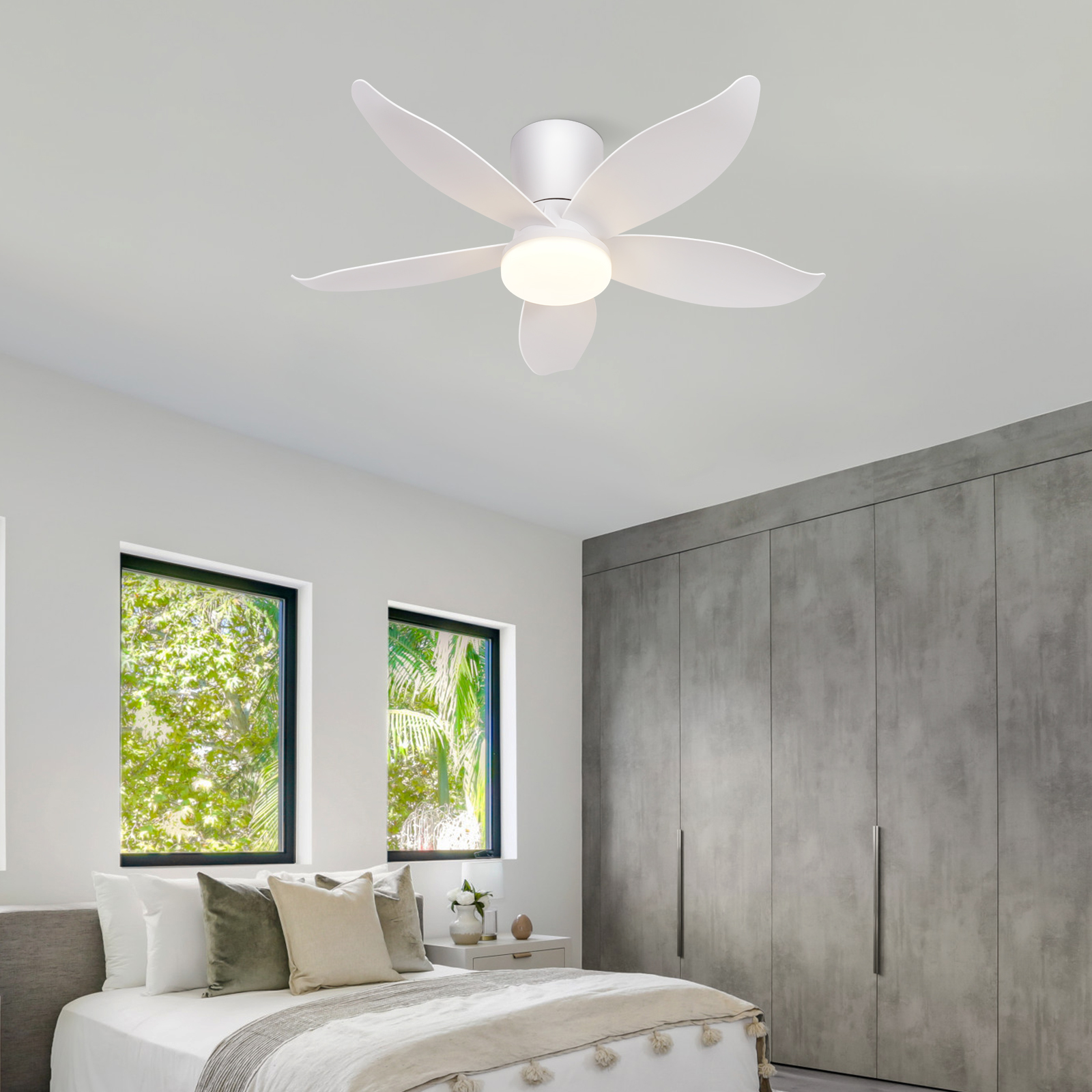 Ein weißer Deckenventilator mit fünf Blättern über einem Bett im Schlafzimmer.