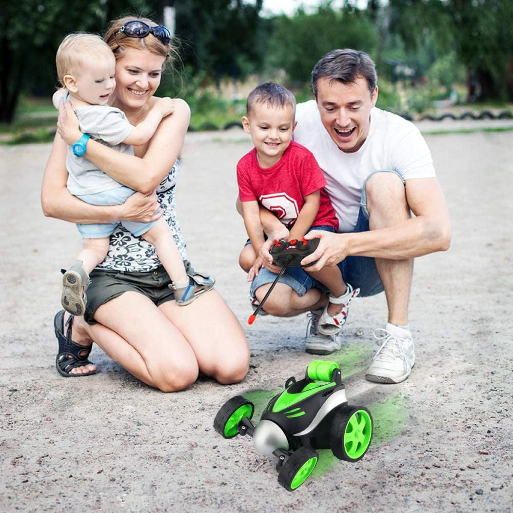 Familie spielt draußen mit einem ferngesteuerten Auto. Eltern und zwei Kinder lächeln.
