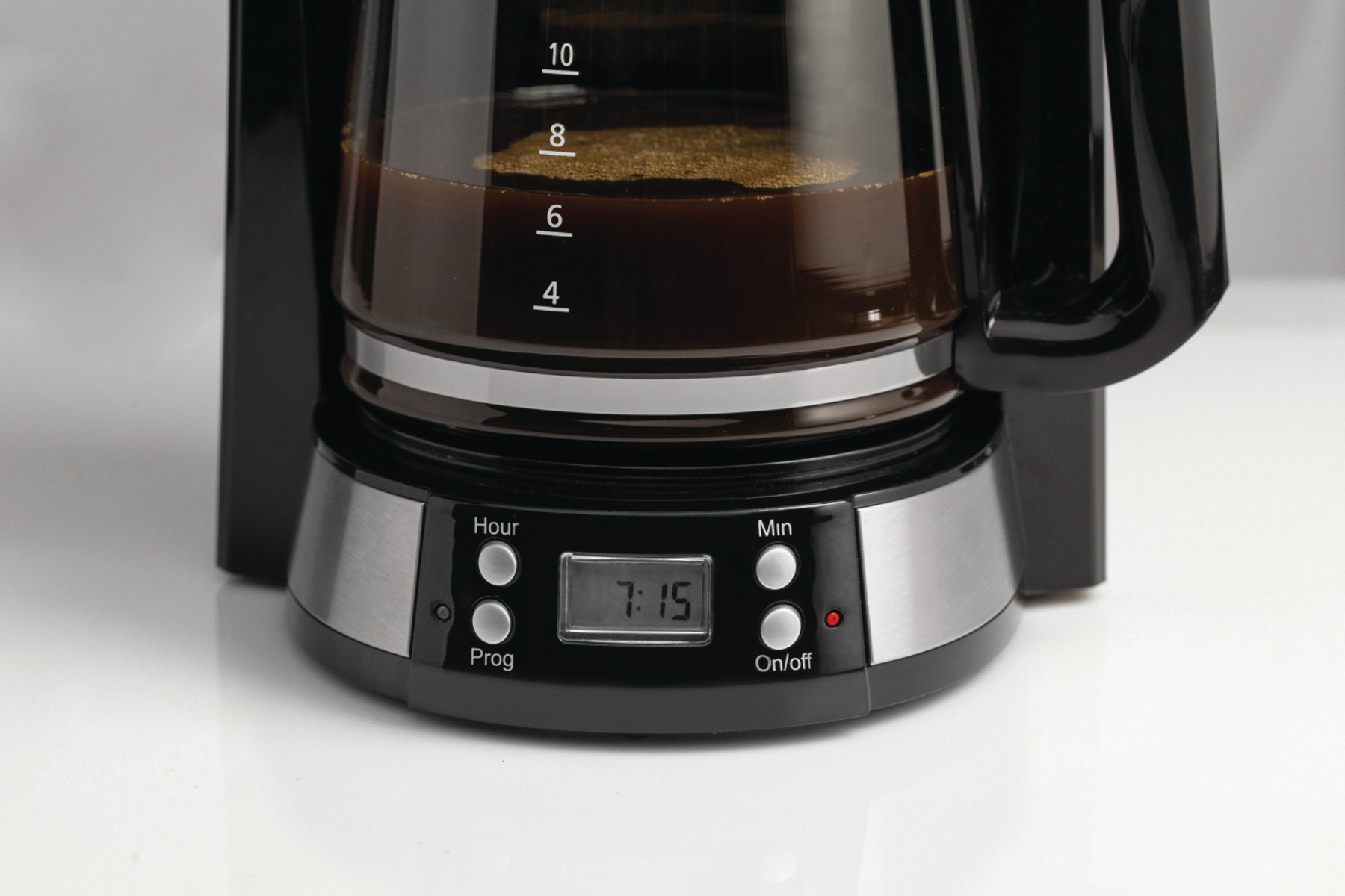 Eine schwarze Kaffeemaschine mit einer vollen Glaskaraffe und einem digitalen Display, das 7:15 anzeigt.