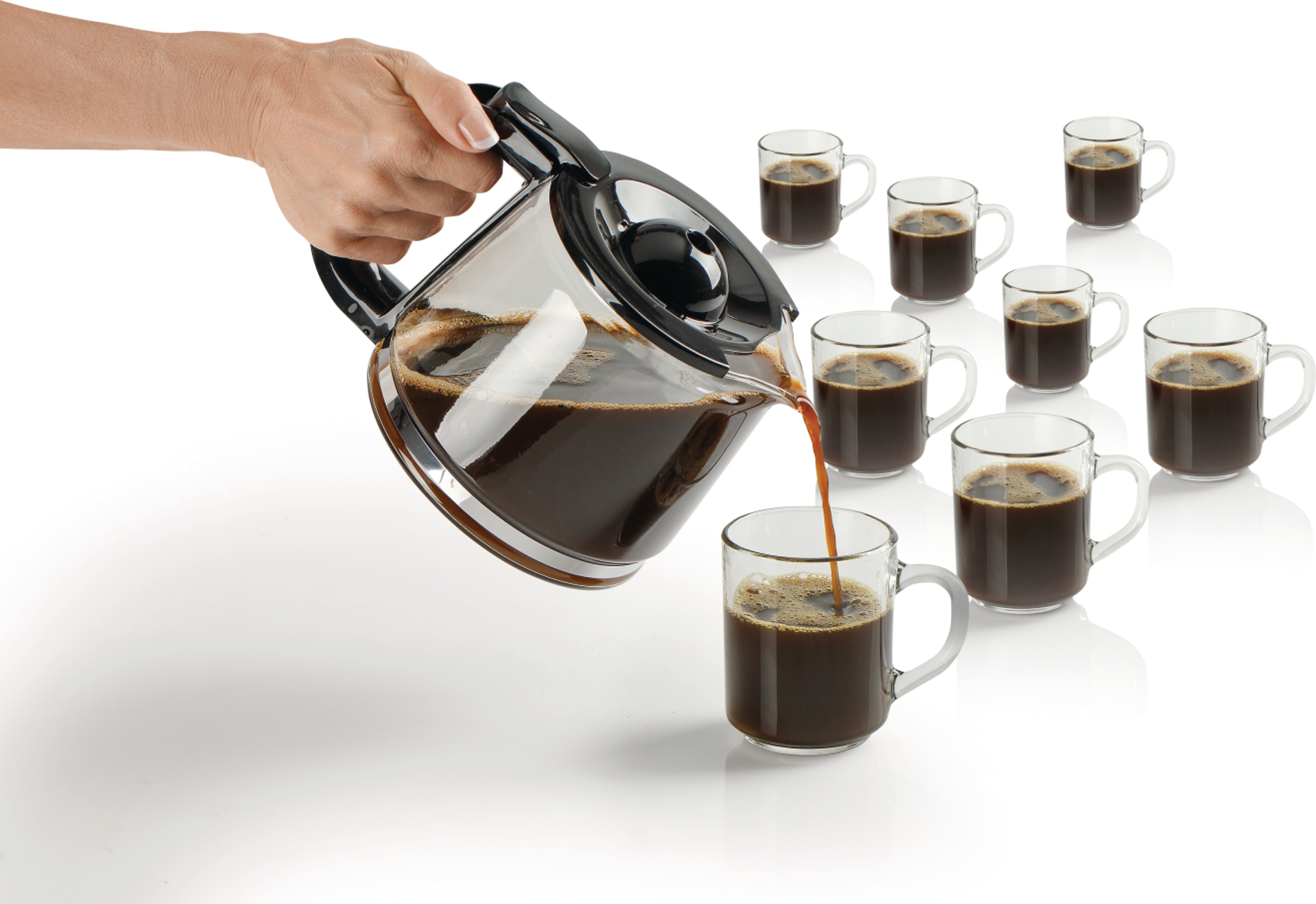 Hand gießt Kaffee aus Glaskanne in Tassen auf weißem Hintergrund.