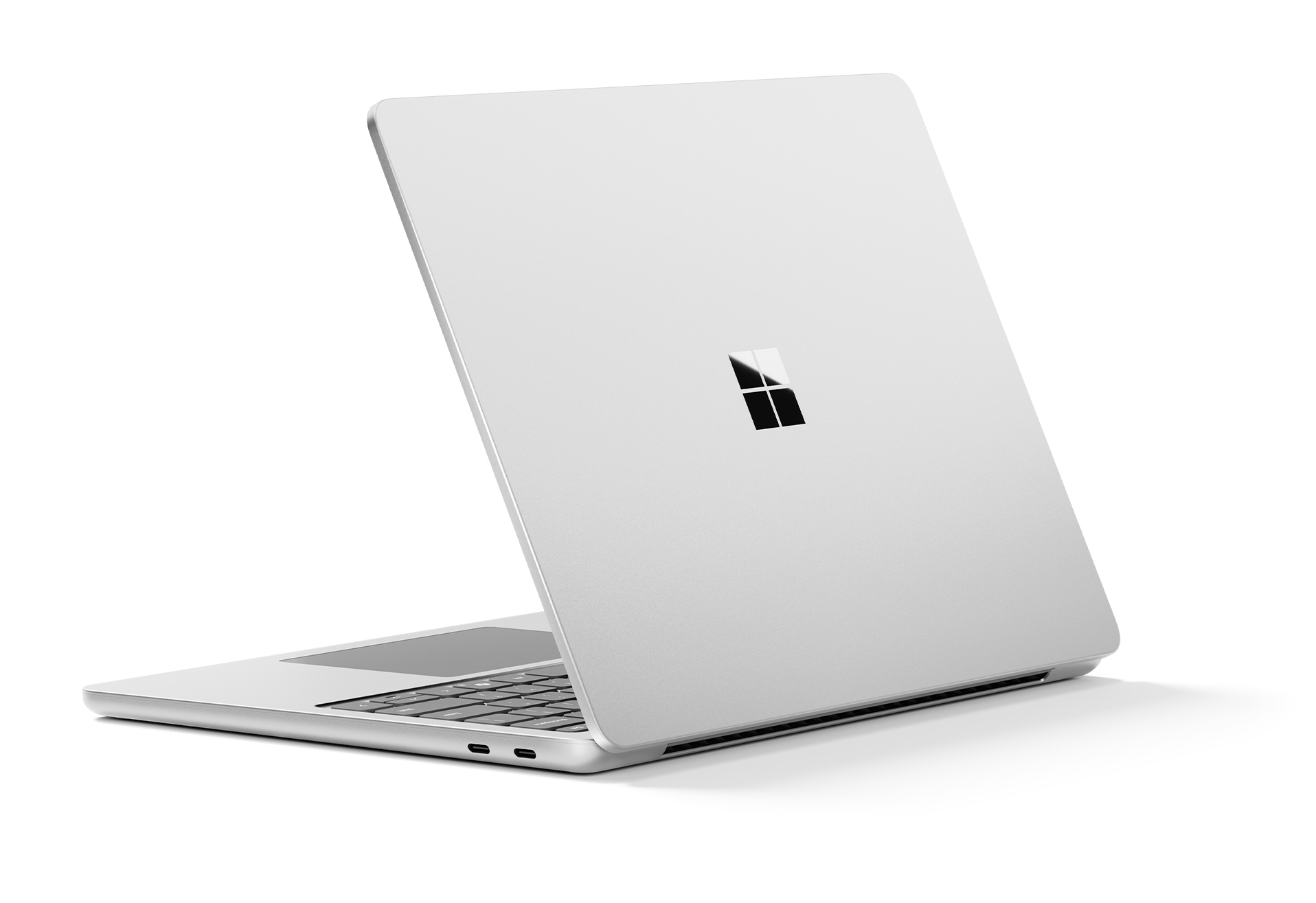 Srebrny laptop z otwartą pokrywą na białym tle. Logo Microsoft znajduje się na pokrywie.