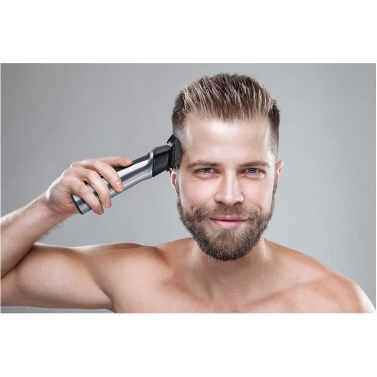 Uomo con barba si taglia i capelli con un rifinitore argentato.