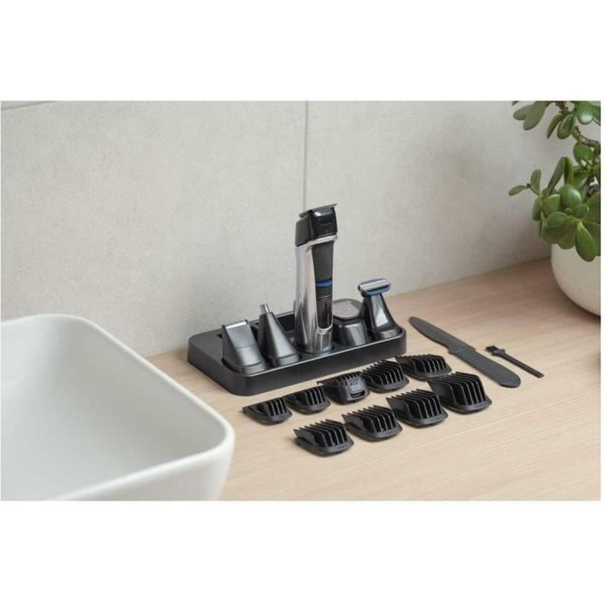 Un rifinitore argento e nero con accessori su un supporto accanto a un lavabo bianco.