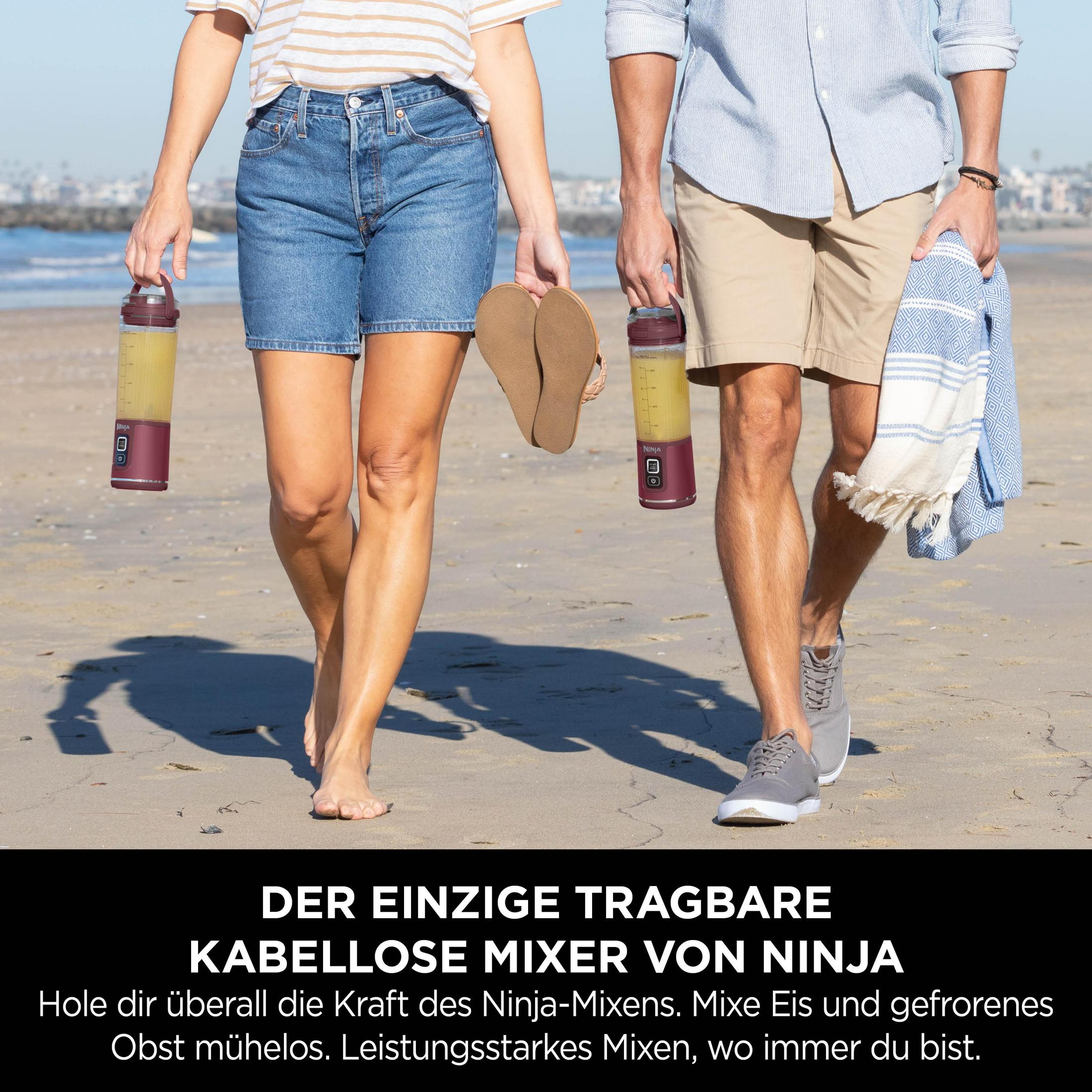 Een stel loopt op het strand met draagbare Ninja blenders.