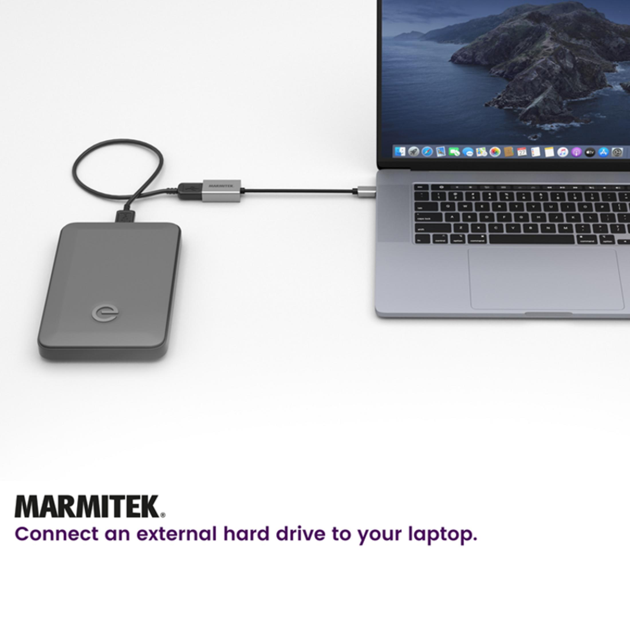 Gray external hard drive connected to a laptop via cable.