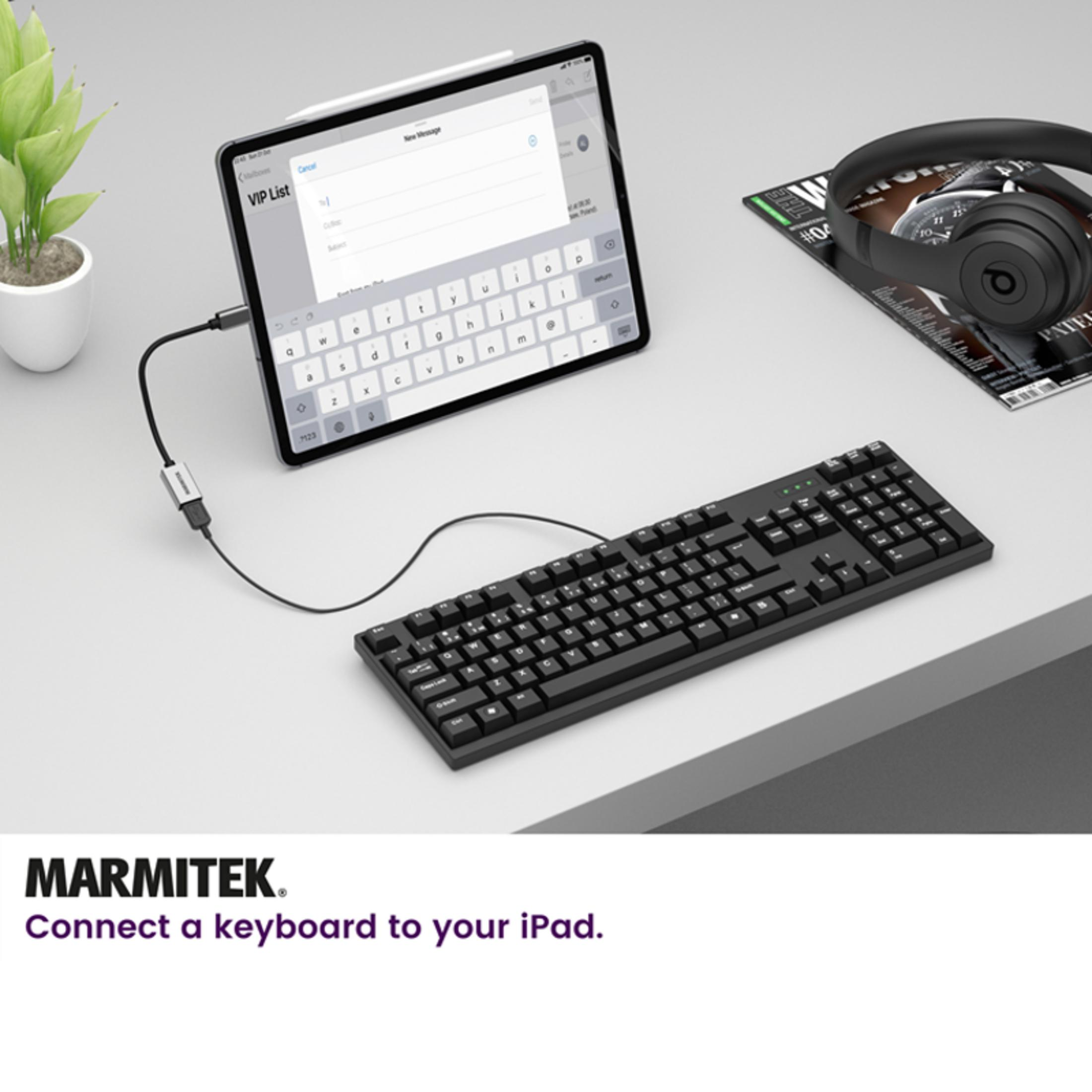 A black iPad with a keyboard and headphones on a desk.