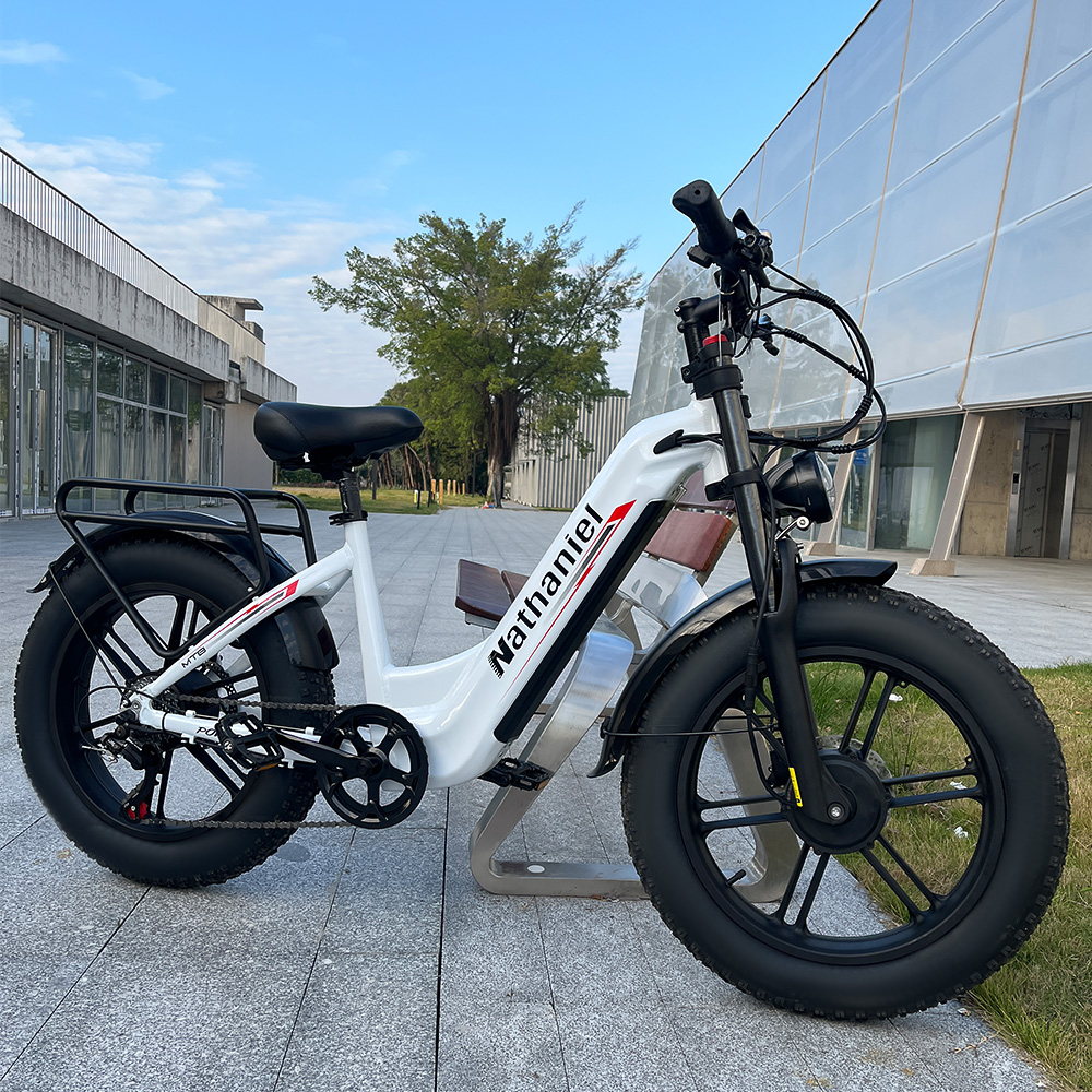 Ein weißes E-Bike mit dicken Reifen steht auf einem Gehweg vor einem modernen Gebäude.