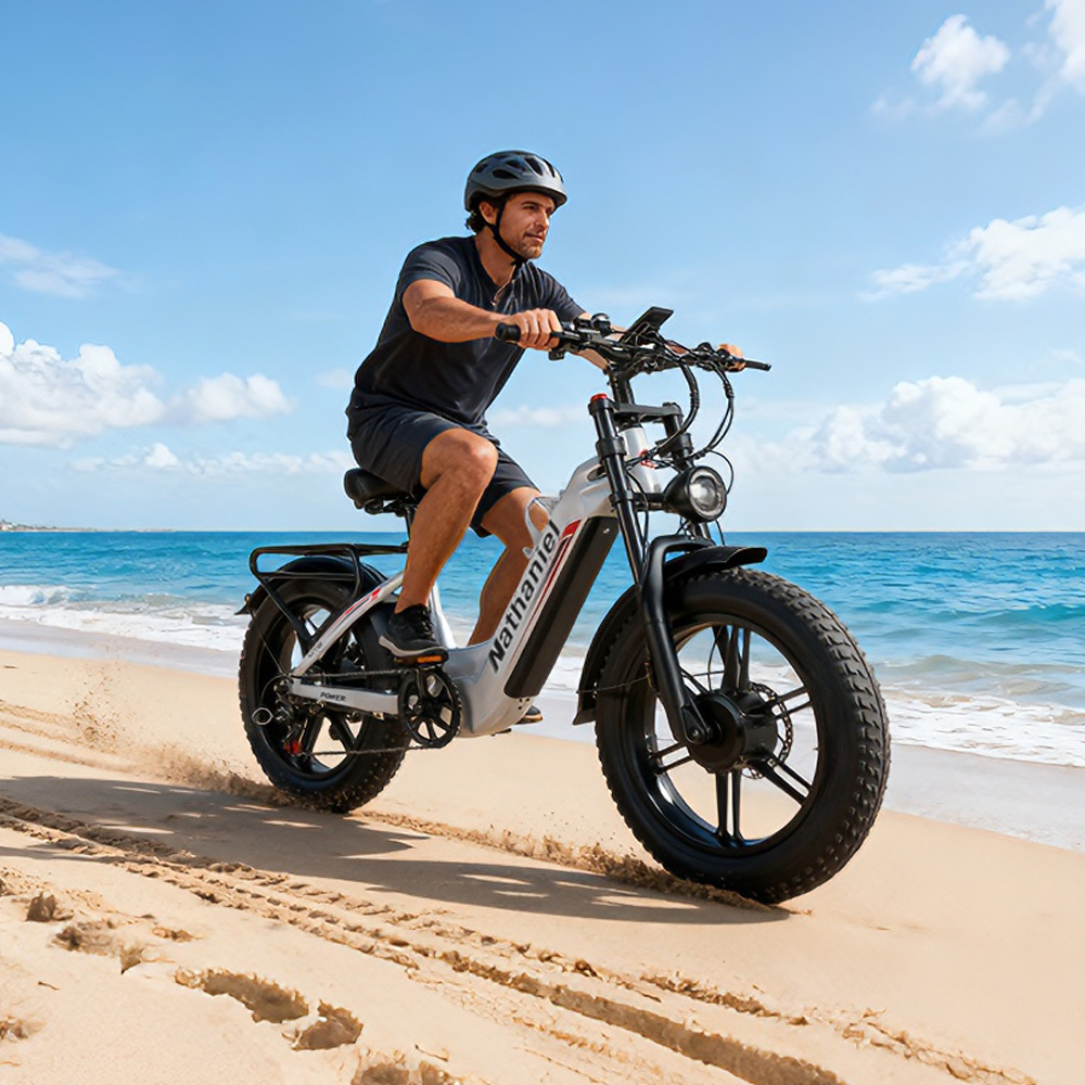 Mann fährt E-Bike am Strand mit Meer im Hintergrund.