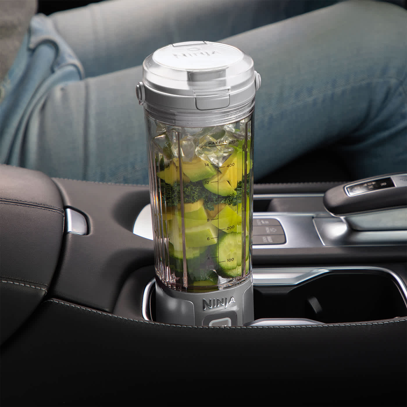 Ein tragbarer Mixer mit Avocado und Gurke gefüllt, steht im Auto-Getränkehalter.