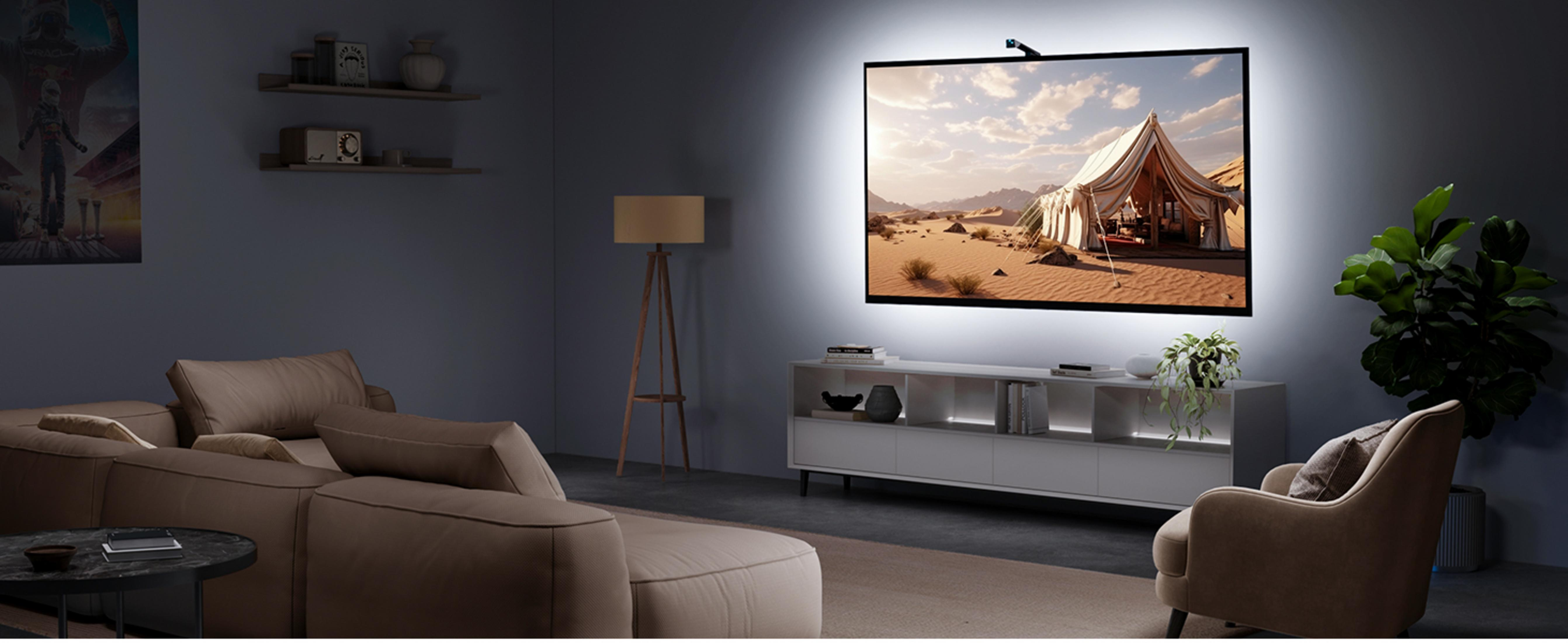 Een woonkamer met een grote bruine bank, een fauteuil en een tv die een woestijntent toont.