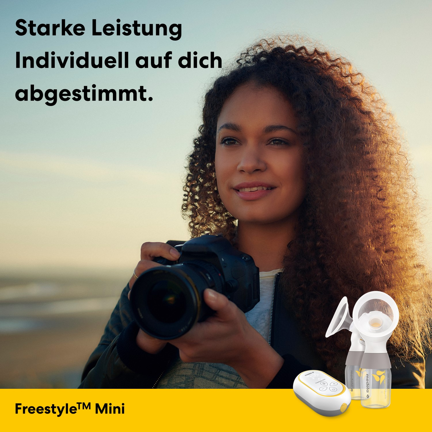 Frau mit Locken hält Kamera, daneben Milchpumpe und Gerät.
